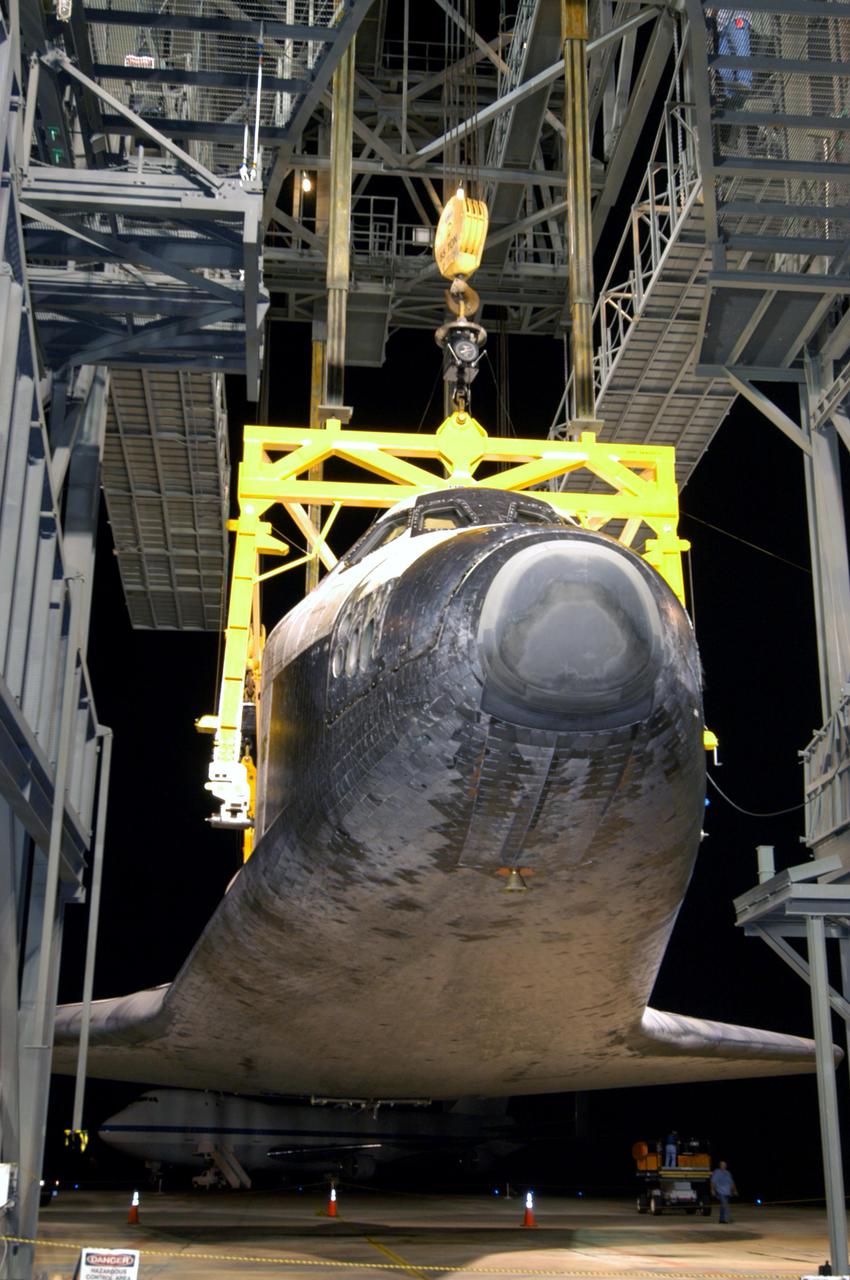 KENNEDY SPACE CENTER, FLA. - In the early morning hours at NASA Kennedy Space Center’s Shuttle Landing Facility, the orbiter Discovery is slowly lowered toward the ground from the mate_demate device. Visible on the orbiter is the tail cone that covers the main engines during the ferry flight.   Discovery was returned to Kennedy Space Center on a ferry flight from Edwards Air Force Base in California, where it landed Aug. 9 after 13 days in space on mission STS-114.  In the mate_demate device, a horizontal structure mounted at the 80-foot level between two towers controls and guides a large lift beam that attaches to the orbiter to raise and lower it.  The orbiter will be lowered to the ground and then be towed to the Orbiter Processing Facility.  Once inside the OPF, the payload bay doors will be opened and the MPLM Raffaello brought back from the International Space Station will be unloaded and transferred to the Space Station Processing Facility.  This concludes mission STS-114.