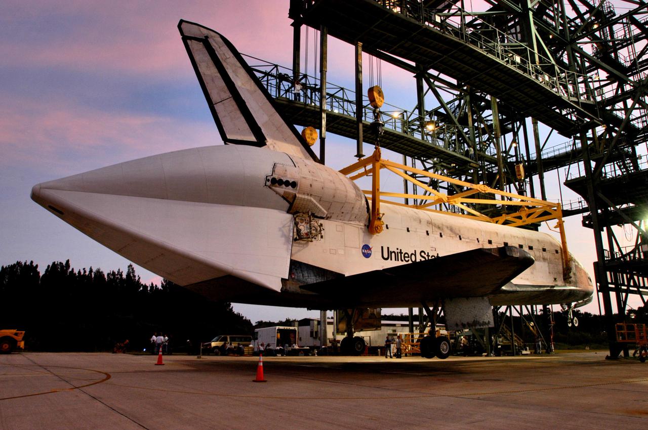 KENNEDY SPACE CENTER, FLA. - Just before sunrise, Discovery finally rests on its wheels on the ground at NASA Kennedy Space Center’s Shuttle Landing Facility.  The orbiter was lowered overnight from the mate_demate device after the Shuttle Carrier Aircraft, a modified Boeing 747, was rolled away.  Discovery was returned to Kennedy Space Center on a ferry flight from Edwards Air Force Base in California, where it landed Aug. 9 after 13 days in space on mission STS-114.  In the mate_demate device, a horizontal structure mounted at the 80-foot level between two towers controls and guides a large lift beam that attaches to the orbiter to raise and lower it.  The orbiter will be lowered to the ground and then be towed to the Orbiter Processing Facility.  Once inside the OPF, the payload bay doors will be opened and the MPLM Raffaello brought back from the International Space Station will be unloaded and transferred to the Space Station Processing Facility.  This concludes mission STS-114.