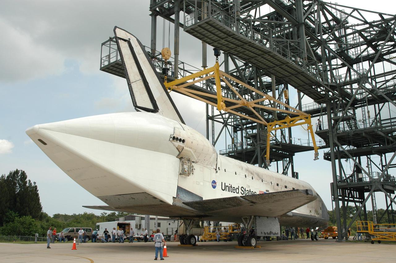 KENNEDY SPACE CENTER, FLA. - Discovery rests on its wheels under the mate_demate device on NASA Kennedy Space Center’s Shuttle Landing Facility. The equipment that lowered it to the ground is being removed. Discovery was returned to NASA Kennedy Space Center on a ferry flight from Edwards Air Force Base in California, arriving Aug. 21. Visible on Discovery is the tail cone that covers and protects the main engines during the ferry flight. Discovery will be towed to the Orbiter Processing Facility where the Multi-Purpose Logistics Module Raffaello still inside will be removed from the payload bay and transferred to the Space Station Processing Facility. The orbiter will then begin processing for the second Return to Flight mission, STS-121, scheduled for launch no earlier than March 2006.