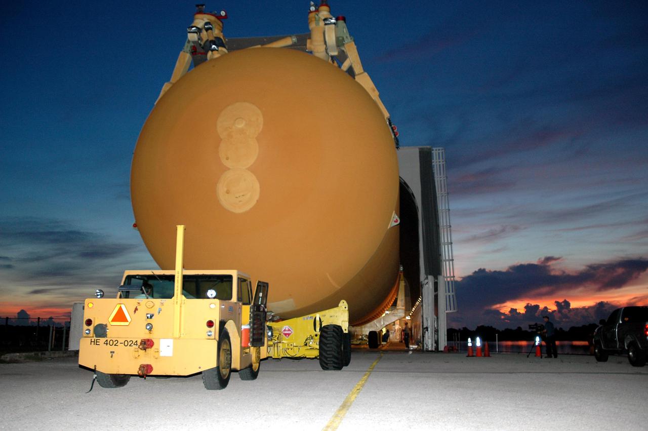 KENNEDY SPACE CENTER, FLA. - Under pre-dawn skies of blue and red, External Tank 119 is towed away from NASA Kennedy Space Center’s Vehicle Assembly Building. It is being moved to the barge at the Turn Basin. The tank will embark on a voyage around the Florida peninsula to the Michoud Assembly Facility in New Orleans. Delivered to KSC in June, ET-119 is the third newly redesigned tank.