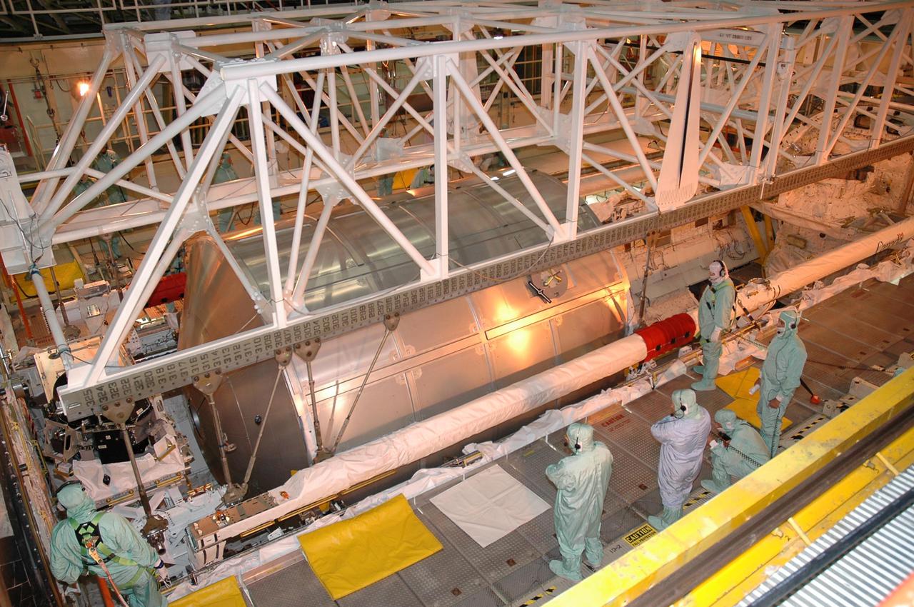 KENNEDY SPACE CENTER, FLA. -- In bay 3 of NASA Kennedy Space Center’s Orbiter Processing Facility, technicians oversee the removal of Return to Flight mission STS-114 cargo from Space Shuttle Discovery's payload bay.  The Multi-Purpose Logistics Module Raffaello, in the payload bay, holds material returned to KSC from the International Space Station. The module will be lifted out of the payload bay and transferred to the Space Station Processing Facility to be emptied. Discovery will fly next on the second Return to Flight mission, STS-121.