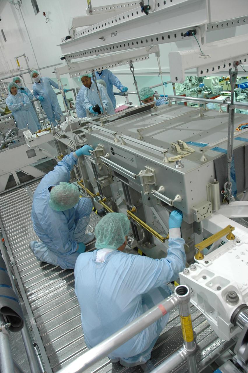 KENNEDY SPACE CENTER, FLA. - In the Space Station Processing Facility, workers prepare to lift the tile box from the Lightweight Multi-Purpose Experiment Support Structure Carrier (LMC) that was returned on Space Shuttle Discovery from mission STS-114. The tile box is the Detailed Test Objective (DTO) tile sample repair kit that astronauts experimented with on the mission. The box is being returned to Johnson Space Center in Houston.