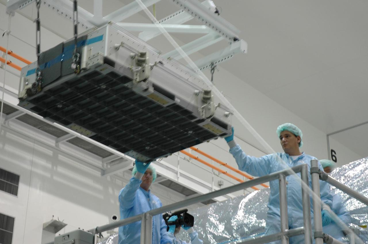 KENNEDY SPACE CENTER, FLA. - In the Space Station Processing Facility, workers oversee the lifting of the tile box from the Lightweight Multi-Purpose Experiment Support Structure Carrier (LMC) that was returned on Space Shuttle Discovery from mission STS-114. The tile box is the Detailed Test Objective (DTO) tile sample repair kit that astronauts experimented with on the mission. The box is being returned to Johnson Space Center in Houston.