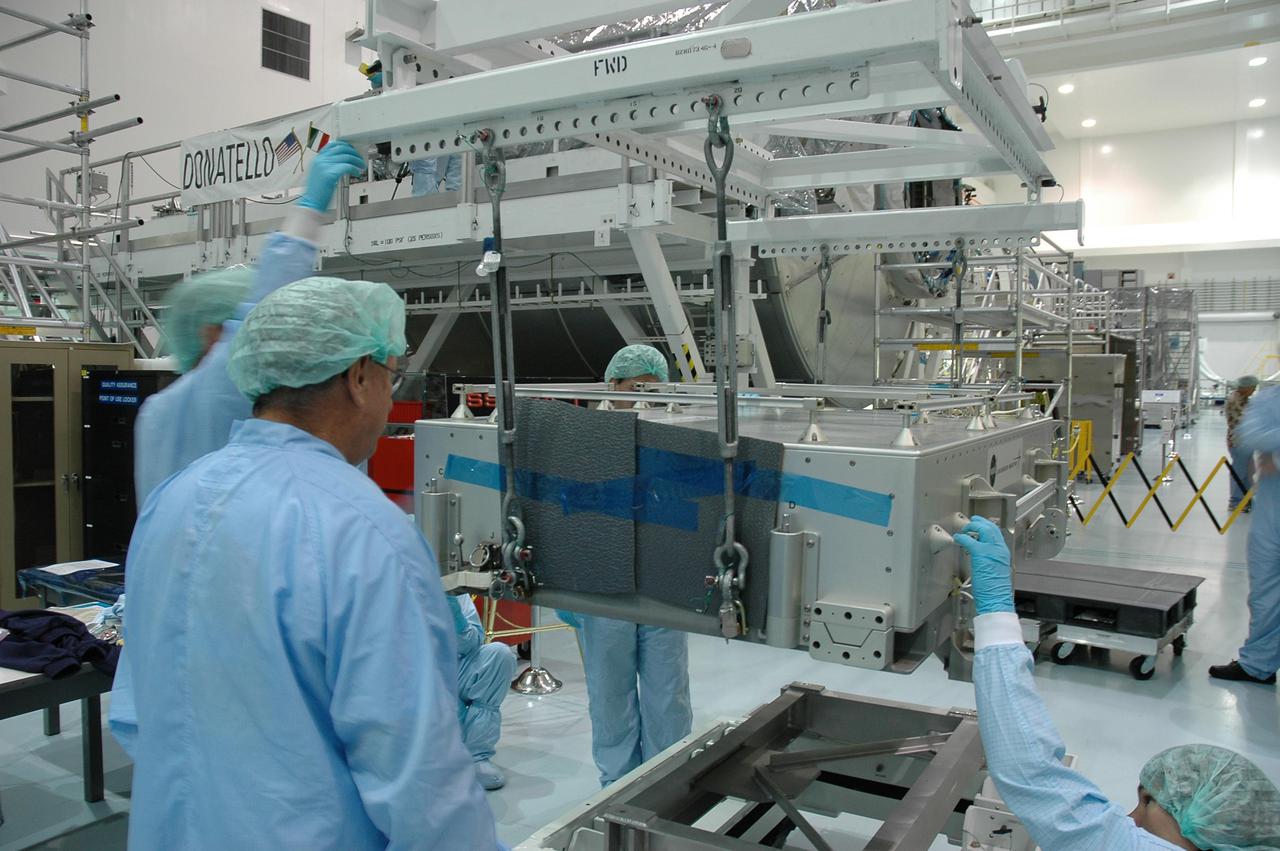 KENNEDY SPACE CENTER, FLA. - In the Space Station Processing Facility, the tile box is lowered onto a stand. The box was removed from the Lightweight Multi-Purpose Experiment Support Structure Carrier (LMC) that was returned on Space Shuttle Discovery from mission STS-114. The tile box is the Detailed Test Objective (DTO) tile sample repair kit that astronauts experimented with on the mission. The box is being returned to Johnson Space Center in Houston.
