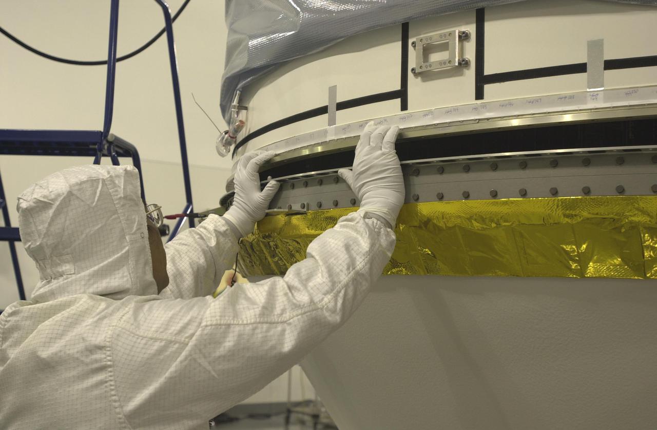 VANDENBERG AIR FORCE BASE, CALIF. - Inside the Astrotech Payload Processing Facility on Vandenberg Air Force Base in California, a worker helps secure the upper Delta Payload Attach Fitting (UDPAF) to the lower Delta Payload Attach Fitting (LDPAF). The LDPAF holds the CloudSat satellite and the UDPAF will hold the CALIPSO satellite. CALIPSO stands for Cloud-Aerosol Lidar and Infrared Pathfinder Satellite Observation. CALIPSO and CloudSat are highly complementary satellites that will provide never-before-seen 3-D perspectives of how clouds and aerosols form, evolve, and affect weather and climate. CALIPSO and CloudSat will fly in formation with three other satellites in the A-train constellation to enhance understanding of our climate system. Launch of CALIPSO_CloudSat aboard a Boeing Delta II rocket is scheduled for 3:01 a.m. PDT Sept. 29.