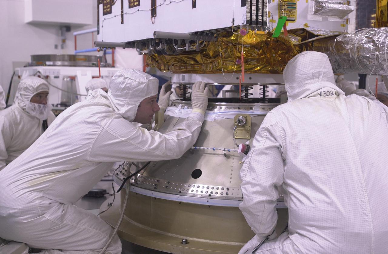 VANDENBERG AIR FORCE BASE, CALIF. —  Inside the Astrotech Payload Processing Facility on Vandenberg Air Force Base in California, workers help secure the CALIPSO spacecraft to the upper Delta Payload Attach Fitting (UDPAF).  Later the UDPAF will be mated with the lower Delta Payload Attach Fitting, which contains the CloudSat satellite.  The PAF is the interface between the spacecraft and the second stage of the rocket.  CALIPSO stands for Cloud-Aerosol Lidar and Infrared Pathfinder Satellite Observation. CALIPSO and CloudSat are highly complementary satellites that will provide never-before-seen 3-D perspectives of how clouds and aerosols form, evolve, and affect weather and climate. CALIPSO and CloudSat will fly in formation with three other satellites in the A-train constellation to enhance understanding of our climate system. Launch of CALIPSO_CloudSat aboard a Boeing Delta II rocket is scheduled for 3:01 a.m. PDT Sept. 29.