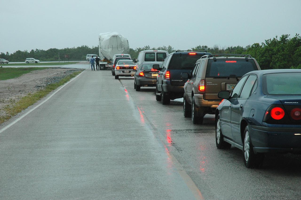 KENNEDY SPACE CENTER, FLA.  — A convoy of vehicles follows behind a truck carrying an Atlas V rocket.  The rocket is being transferred to the Atlas Space Operations Center. The Atlas V is the launch vehicle for the New Horizons spacecraft.   New Horizons is designed to help us understand worlds at the edge of our solar system by making the first reconnaissance of Pluto and Charon - a 'double planet' and the last planet in our solar system to be visited by spacecraft. The mission will then visit one or more objects in the Kuiper Belt region beyond Neptune. New Horizons is scheduled to launch from Launch Complex 41 at CCAFS in January 2006, swing past Jupiter for a gravity boost and scientific studies in February or March 2007, and reach Pluto and its moon, Charon, in July 2015.