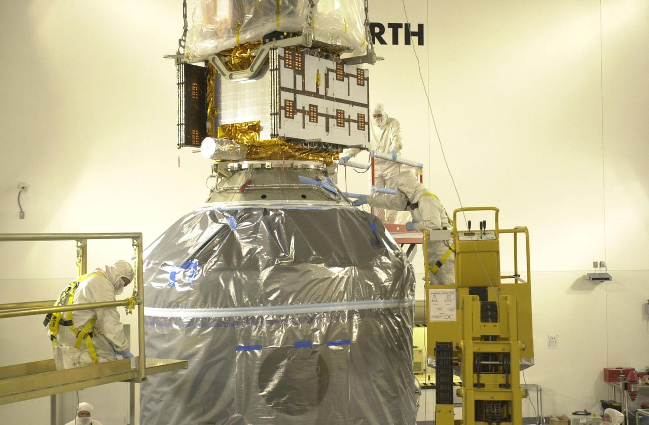 VANDENBERG AIR FORCE BASE, CALIF.  — Inside the Astrotech Payload Processing Facility on Vandenberg Air Force Base in California, workers check the lowering of the CALIPSO spacecraft and Upper Delta Payload Attach Fitting (UDPAF) onto the Lower Delta Payload Attach Fitting (LDPAF) that contains the CloudSat satellite.   The PAF is the interface between the spacecraft and the second stage of the rocket. CALIPSO stands for Cloud-Aerosol Lidar and Infrared Pathfinder Satellite Observation.