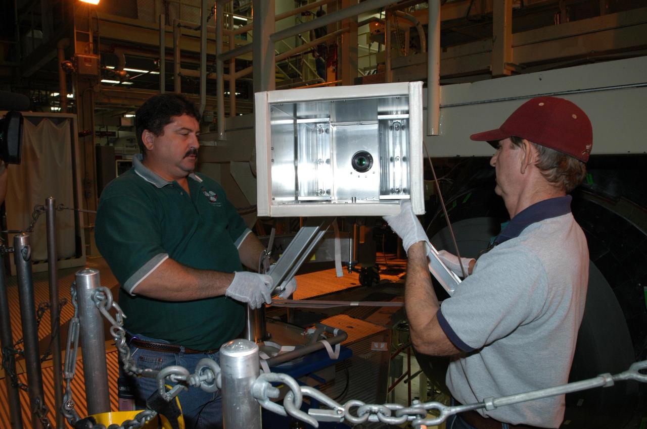 KENNEDY SPACE CENTER, FLA. - In NASA Kennedy Space Center’s Orbiter Processing Facility, bay 3, Don Nielen (left) and Dick Logsdon, both with United Space Alliance, set up equipment to be used for thermography of Discovery’s nose cone. Thermography uses high-intensity light to heat specific areas, which are then immediately scanned with an infrared camera. As the area cools, internal flaws are revealed. Discovery has been identified as the orbiter to fly on mission STS-121.