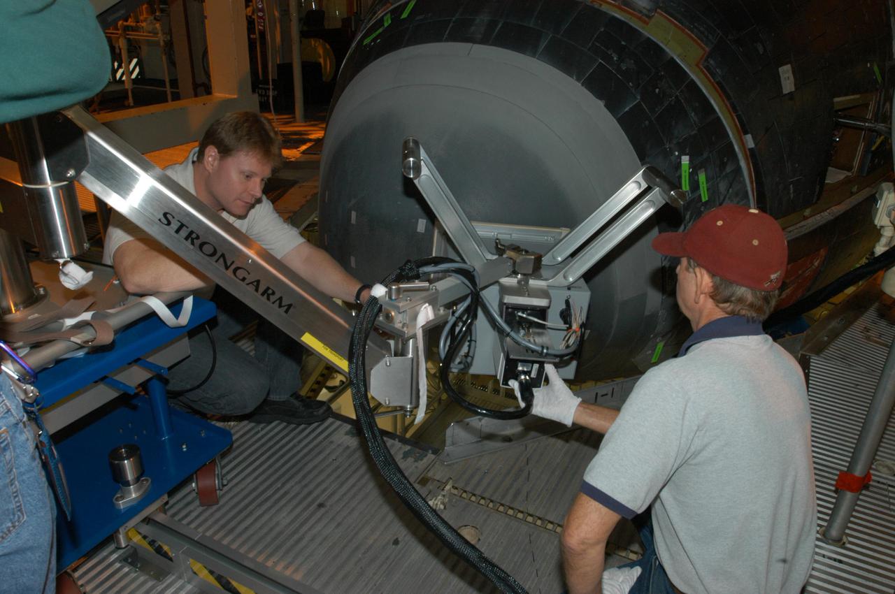 KENNEDY SPACE CENTER, FLA. - In NASA Kennedy Space Center’s Orbiter Processing Facility, bay 3, NDE Specialist Jim Landy (left) and Dick Logsdon, with United Space Alliance, set up thermography equipment in front of Discovery’s nose cone. Thermography uses high-intensity light to heat specific areas, which are then immediately scanned with an infrared camera. As the area cools, internal flaws are revealed. Discovery has been identified as the orbiter to fly on mission STS-121.
