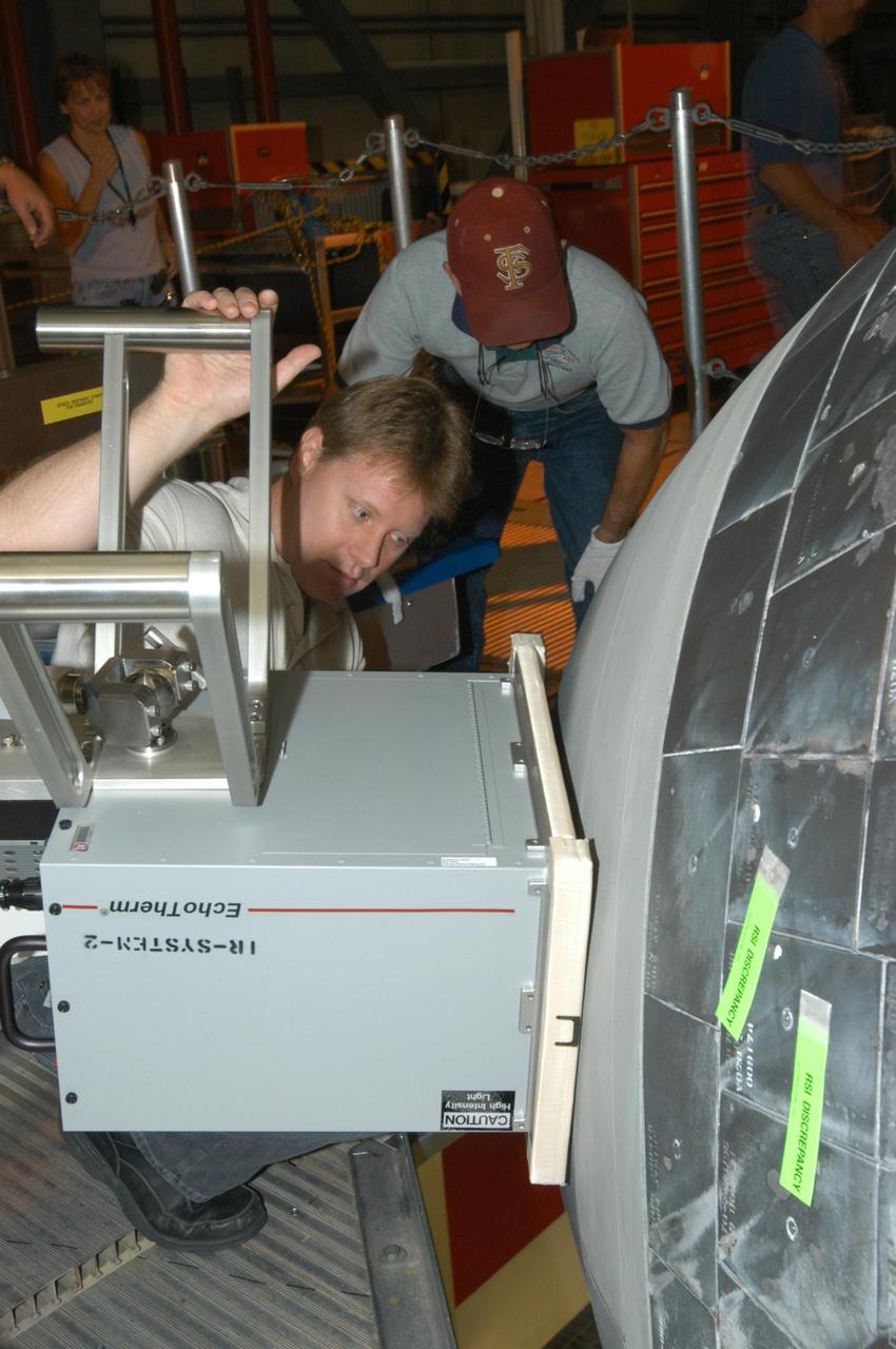 KENNEDY SPACE CENTER, FLA. - In NASA Kennedy Space Center’s Orbiter Processing Facility, bay 3, United Space Alliance workers Jim Landy (front) and Dick Logsdon (back) adjust thermography equipment in front of Discovery’s nose cone. Thermography uses high-intensity light to heat specific areas, which are then immediately scanned with an infrared camera. As the area cools, internal flaws are revealed. Discovery has been identified as the orbiter to fly on mission STS-121.
