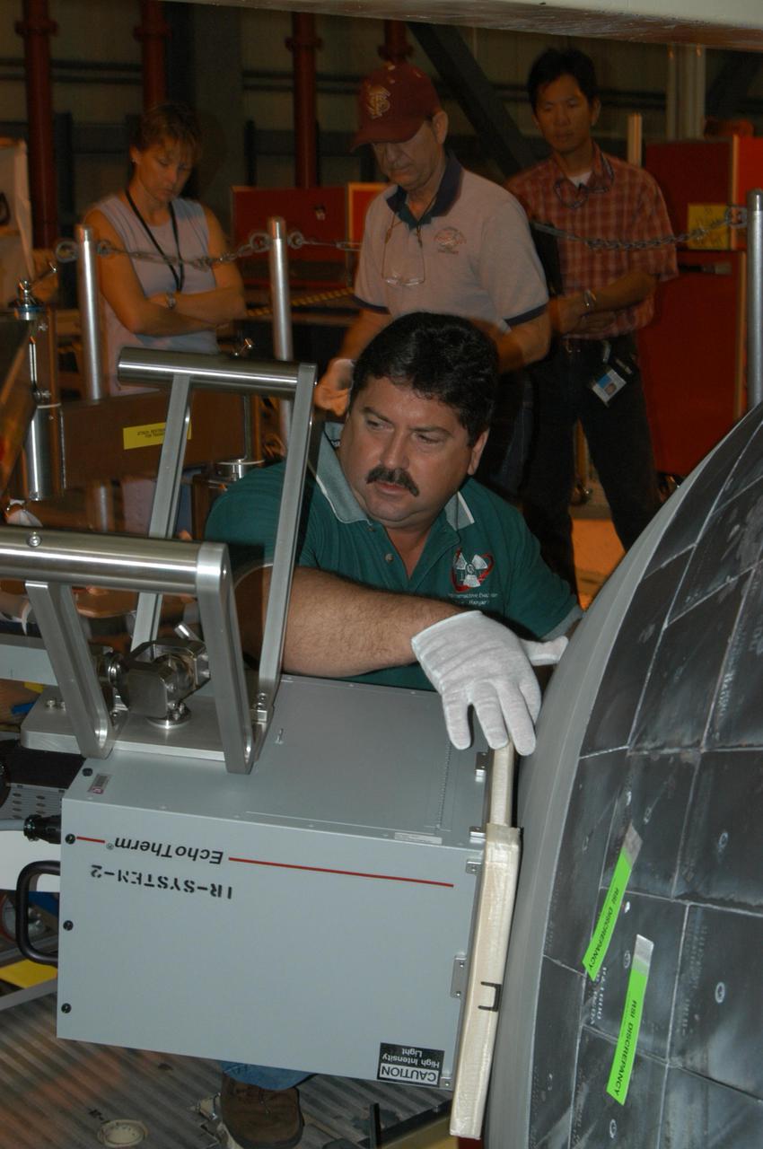 KENNEDY SPACE CENTER, FLA. - In NASA Kennedy Space Center’s Orbiter Processing Facility, bay 3, Don Neilen (front), with United Space Alliance, adjusts thermography equipment in front of Discovery’s nose cone. In the background are (from left) Lisa Huddleston, Dick Logsdon and Mike Hess, also with USA. Thermography uses high-intensity light to heat specific areas, which are then immediately scanned with an infrared camera. As the area cools, internal flaws are revealed. Discovery has been identified as the orbiter to fly on mission STS-121.