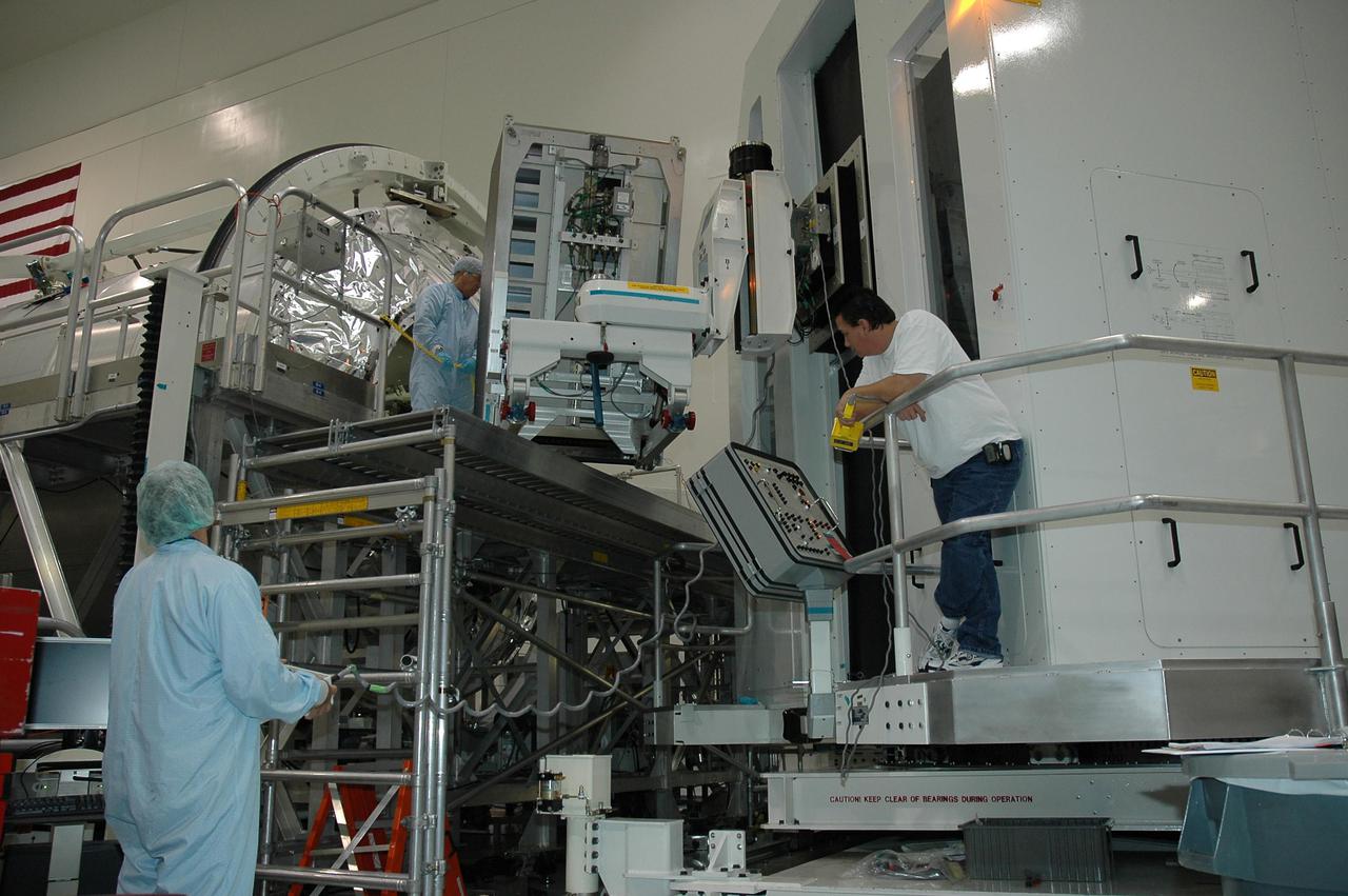 KENNEDY SPACE CENTER, FLA. - In NASA Kennedy Space Center’s Space Station Processing Facility, workers wait for a rack of storage material taken from inside the multi-purpose logistics module Raffaello to be lowered. Raffaello flew on return to flight mission STS-114. During the mission, the crews of Discovery and Expedition 11 transferred more than a ton of material from the International Space Station to be returned to Earth. The workers are unloading the storage racks.