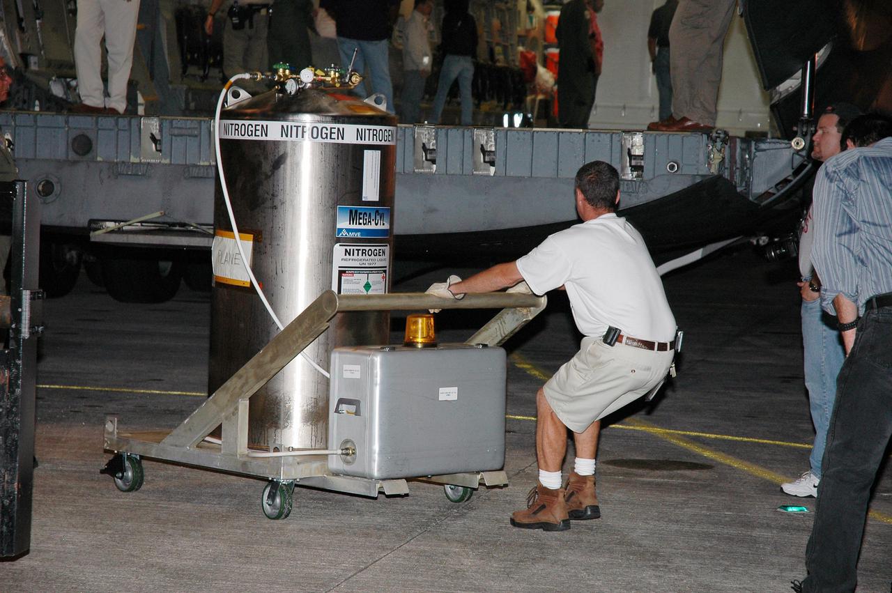 KENNEDY SPACE CENTER, FLA. -  At NASA Kennedy Space Center’s Shuttle Landing Facility, workers move a nitrogen tank to a nearby transporter.  The equipment is part of the cargo delivered aboard a U.S. Air Force C-17 cargo plane (in the background), primarily the Pluto New Horizons spacecraft.  After it is unloaded, the spacecraft will be transported to the Payload Hazardous Servicing Facility.  The nitrogen provides a purge to keep components cool and dry during processing.New Horizons is designed to help us understand worlds at the edge of our solar system by making the first reconnaissance of Pluto and Charon - a 'double planet' and the last planet in our solar system to be visited by spacecraft. The mission will then visit one or more objects in the Kuiper Belt region beyond Neptune. New Horizons is scheduled to launch in January 2006, swing past Jupiter for a gravity boost and scientific studies in February or March 2007, and reach Pluto and its moon, Charon, in July 2015.