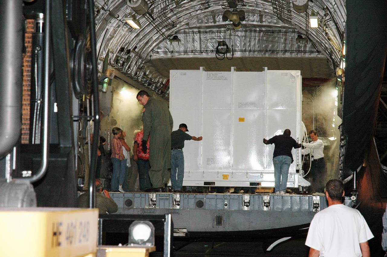 KENNEDY SPACE CENTER, FLA. -  In the U.S. Air Force C-17 cargo plane at NASA Kennedy Space Center’s Shuttle Landing Facility, workers move the large shipping container with the New Horizons spacecraft inside. After it is unloaded, the spacecraft will be transported to the Payload Hazardous Servicing Facility. New Horizons is designed to help us understand worlds at the edge of our solar system by making the first reconnaissance of Pluto and Charon - a 'double planet' and the last planet in our solar system to be visited by spacecraft. The mission will then visit one or more objects in the Kuiper Belt region beyond Neptune. New Horizons is scheduled to launch in January 2006, swing past Jupiter for a gravity boost and scientific studies in February or March 2007, and reach Pluto and its moon, Charon, in July 2015.