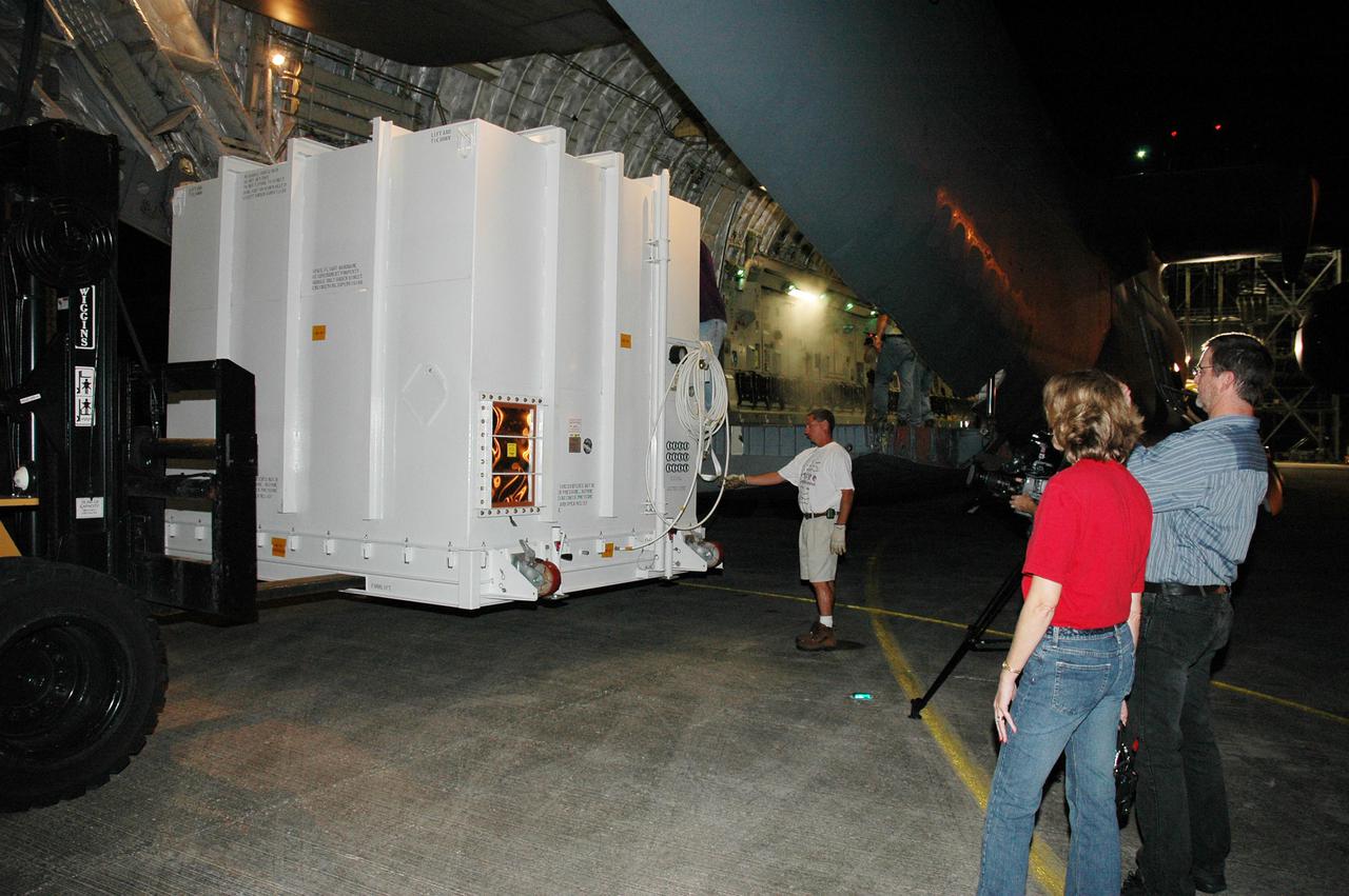 KENNEDY SPACE CENTER, FLA. -  At NASA Kennedy Space Center’s Shuttle Landing Facility, the shipping container with the New Horizons spacecraft inside is moved away from the U.S. Air Force C-17 cargo plane.  The spacecraft will be placed on a transporter and moved to the Payload Hazardous Servicing Facility.  New Horizons is designed to help us understand worlds at the edge of our solar system by making the first reconnaissance of Pluto and Charon - a 'double planet' and the last planet in our solar system to be visited by spacecraft. The mission will then visit one or more objects in the Kuiper Belt region beyond Neptune. New Horizons is scheduled to launch in January 2006, swing past Jupiter for a gravity boost and scientific studies in February or March 2007, and reach Pluto and its moon, Charon, in July 2015.