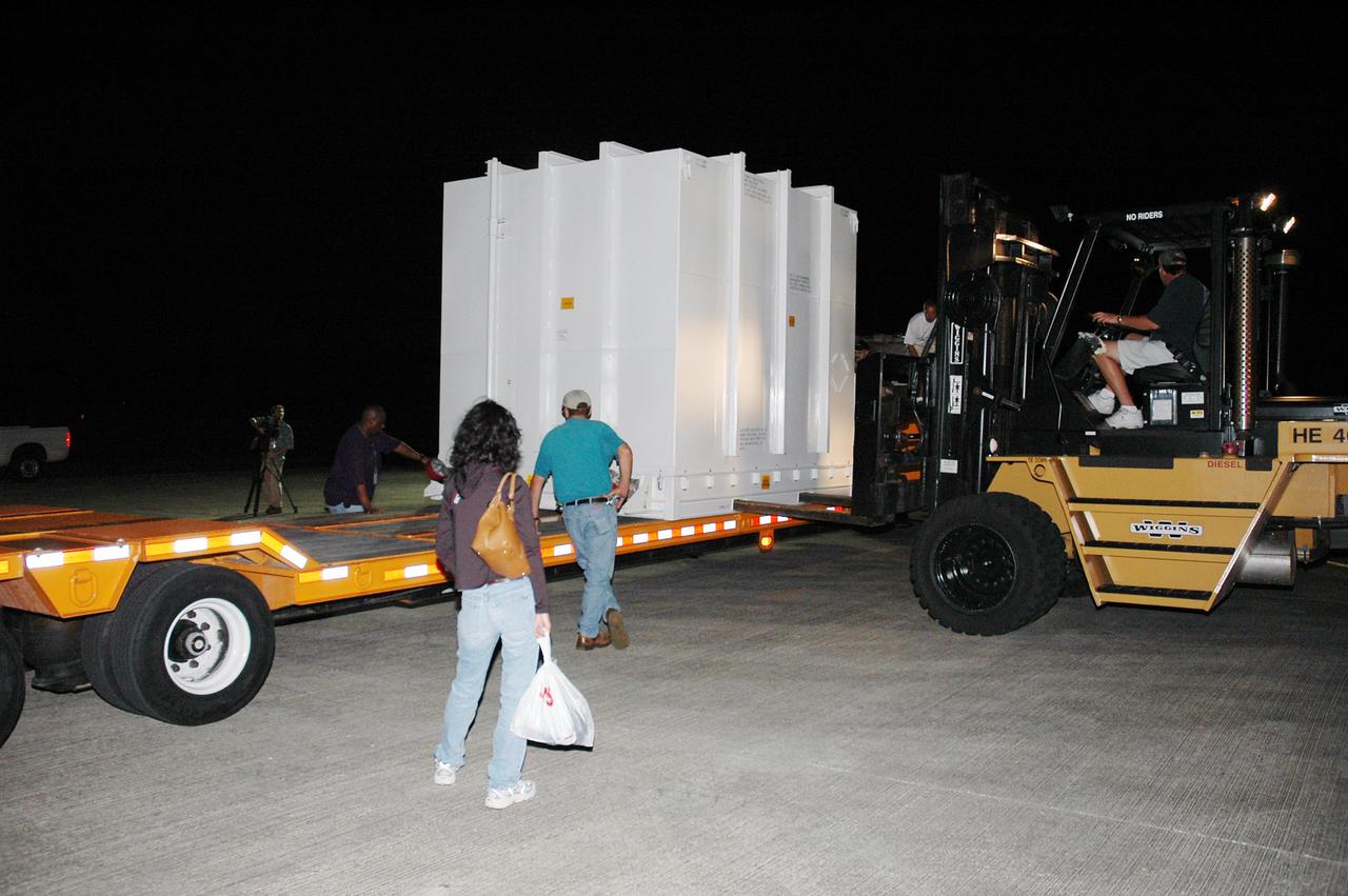 KENNEDY SPACE CENTER, FLA. - At NASA Kennedy Space Center’s Shuttle Landing Facility, the shipping container with the New Horizons spacecraft inside is placed on a transporter. It will be moved to the Payload Hazardous Servicing Facility. New Horizons is designed to help us understand worlds at the edge of our solar system by making the first reconnaissance of Pluto and Charon - a 'double planet' and the last planet in our solar system to be visited by spacecraft. The mission will then visit one or more objects in the Kuiper Belt region beyond Neptune. New Horizons is scheduled to launch in January 2006, swing past Jupiter for a gravity boost and scientific studies in February or March 2007, and reach Pluto and its moon, Charon, in July 2015.