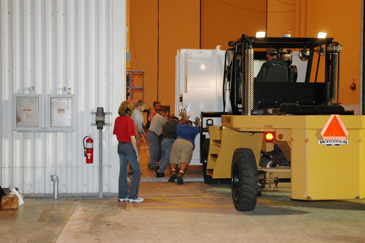 KENNEDY SPACE CENTER, FLA. - At NASA Kennedy Space Center’s Payload Hazardous Servicing Facility, the shipping container with the New Horizons spacecraft inside is offloaded from the transporter. The spacecraft will be moved into the facility and uncrated. New Horizons is designed to help us understand worlds at the edge of our solar system by making the first reconnaissance of Pluto and Charon - a 'double planet' and the last planet in our solar system to be visited by spacecraft. The mission will then visit one or more objects in the Kuiper Belt region beyond Neptune. New Horizons is scheduled to launch in January 2006, swing past Jupiter for a gravity boost and scientific studies in February or March 2007, and reach Pluto and its moon, Charon, in July 2015.