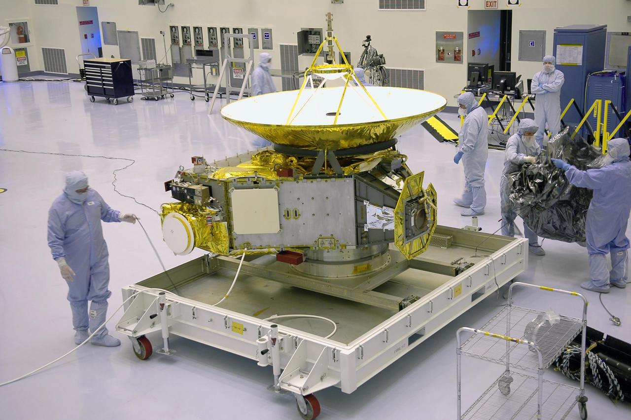 KENNEDY SPACE CENTER, FLA. - In NASA Kennedy Space Center’s Payload Hazardous Servicing Facility, workers finish removing the protective cover around the New Horizons spacecraft. The spacecraft will be moved to a work stand for a checkout. New Horizons will make the first reconnaissance of Pluto and Charon - a 'double planet' and the last planet in our solar system to be visited by spacecraft. The mission will then visit one or more objects in the Kuiper Belt region beyond Neptune. New Horizons is scheduled to launch in January 2006, swing past Jupiter for a gravity boost and scientific studies in February or March 2007, and reach Pluto and its moon, Charon, in July 2015.