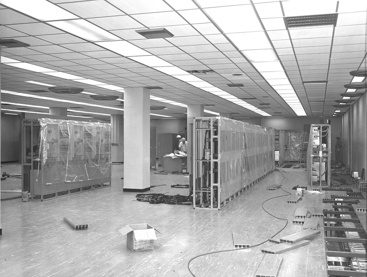 At its founding, the Marshall Space Flight Center (MSFC) inherited the Army’s Jupiter and Redstone test stands, but much larger facilities were needed for the giant stages of the Saturn V. From 1960 to 1964, the existing stands were remodeled and a sizable new test area was developed. The new comprehensive test complex for propulsion and structural dynamics was unique within the nation and the free world, and they remain so today because they were constructed with foresight to meet the future as well as on going needs. Construction of the S-IC Static test stand complex began in 1961 in the west test area of MSFC, and was completed in 1964. The S-IC static test stand was designed to develop and test the 138-ft long and 33-ft diameter Saturn V S-IC first stage, or booster stage, weighing in at 280,000 pounds. Required to hold down the brute force of a 7,500,000-pound thrust produced by 5 F-1 engines, the S-IC static test stand was designed and constructed with the strength of hundreds of tons of steel and 12,000,000 pounds of cement, planted down to bedrock 40 feet below ground level. The foundation walls, constructed with concrete and steel, are 4 feet thick. The base structure consists of four towers with 40-foot-thick walls extending upward 144 feet above ground level. The structure was topped by a crane with a 135-foot boom. With the boom in the upright position, the stand was given an overall height of 405 feet, placing it among the highest structures in Alabama at the time. In addition to the stand itself, related facilities were constructed during this time. Built directly east of the test stand was the Block House, which served as the control center for the test stand. The two were connected by a narrow access tunnel which housed the cables for the controls. This photograph, taken August 12, 1963, offers a view of the Block House interior.