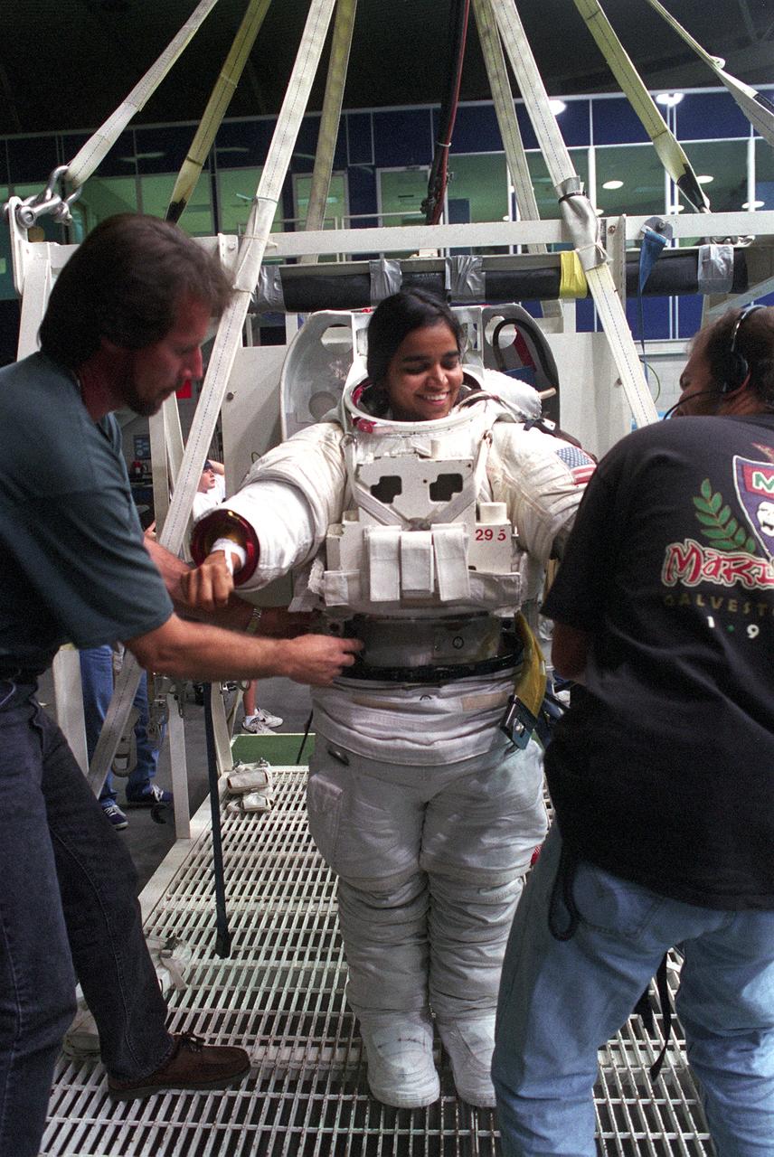 Astronaut and mission specialist Kalpana Chawla, receives assistance in donning a training version of the Extravehicular Mobility Unit (EMU) space suit, prior to an underwater training session in the Neutral Buoyancy Laboratory (NBL) near Johnson Space Center. This particular training was in preparation for the STS-87 mission. The Space Shuttle Columbia (STS-87) was the fourth flight of the United States Microgravity Payload (USMP-4) and Spartan-201 satellite, both managed by scientists and engineers from the Marshall Space Flight Center.           