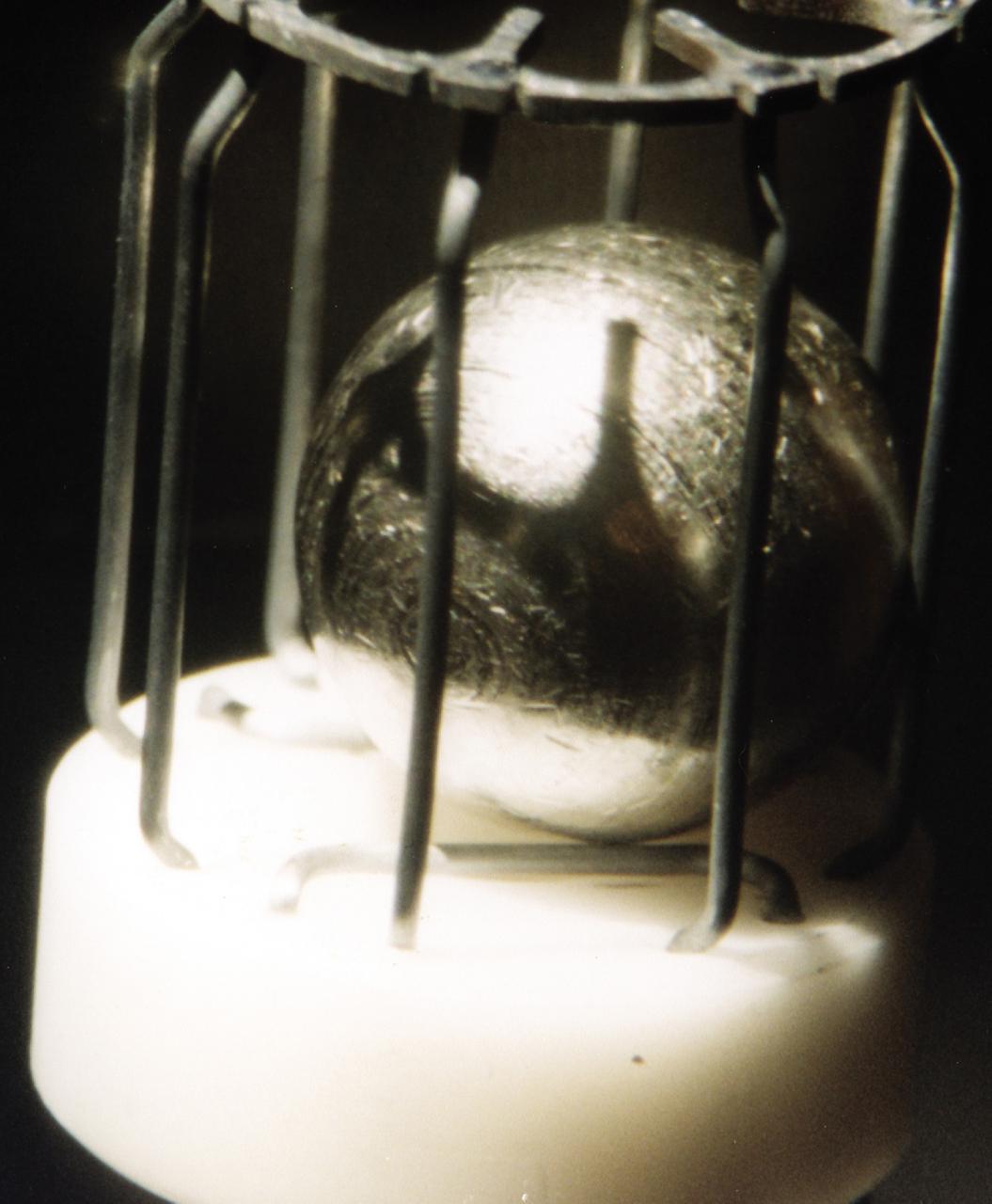 This metal sample, which is approximately 1 cm in diameter, is typical of the metals that were  studied using the German designed electromagnetic containerless processing facility.  The series of experiments that use this device is known as TEMPUS which is the acronym that stands for the German Tiegelfreies Elektromanetisches Prozessieren Unter Schwerelosigkeit. Most of the TEMPUS experiments focused on various aspects of undercooling liquid metal and alloys. Undercooling is the process of melting a material and then cooling it to a temperature that is below its normal freezing or solidification point. The TEMPUS experiments that used the metal cages as shown in the photograph, often studied bulk metallic glass, a solid material with no crystalline structures. We study metals and alloys not only to build things in space, but to improve things that are made on Earth. Metals and alloys are everywhere around us; in our automobiles, in the engines of aircraft, in our power-plants, and elsewhere. Despite their presence in everyday life, there are many scientific aspects of metals that we do not understand.    