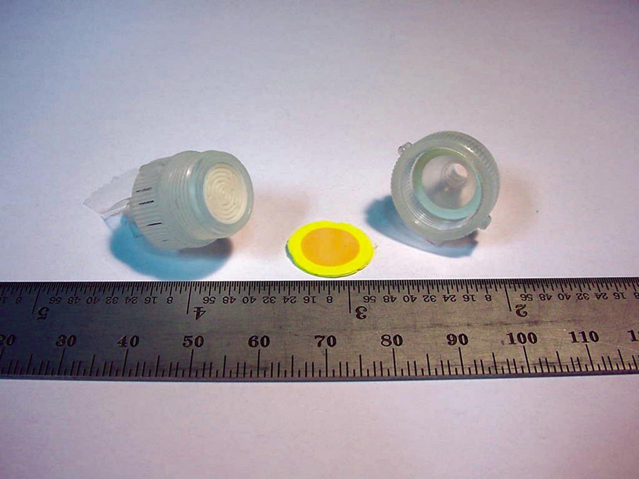 The heart of a colorimetric solid phase extractor (CSPE) test kit quickly measures the concentration of the biocides silver or iodine in astronauts’ drinking water to determine whether concentrations are safe. When 10 milliliters (ml) of water is drawn through the disk, the disk will turn color (yellow in this picture for iodine) indicating the presence of the biocides.  The device could someday be used to test water safety at reservoirs and water treatment plants on Earth. (photo credit: Microanalytical Instrumentation Center, Iowa State University).