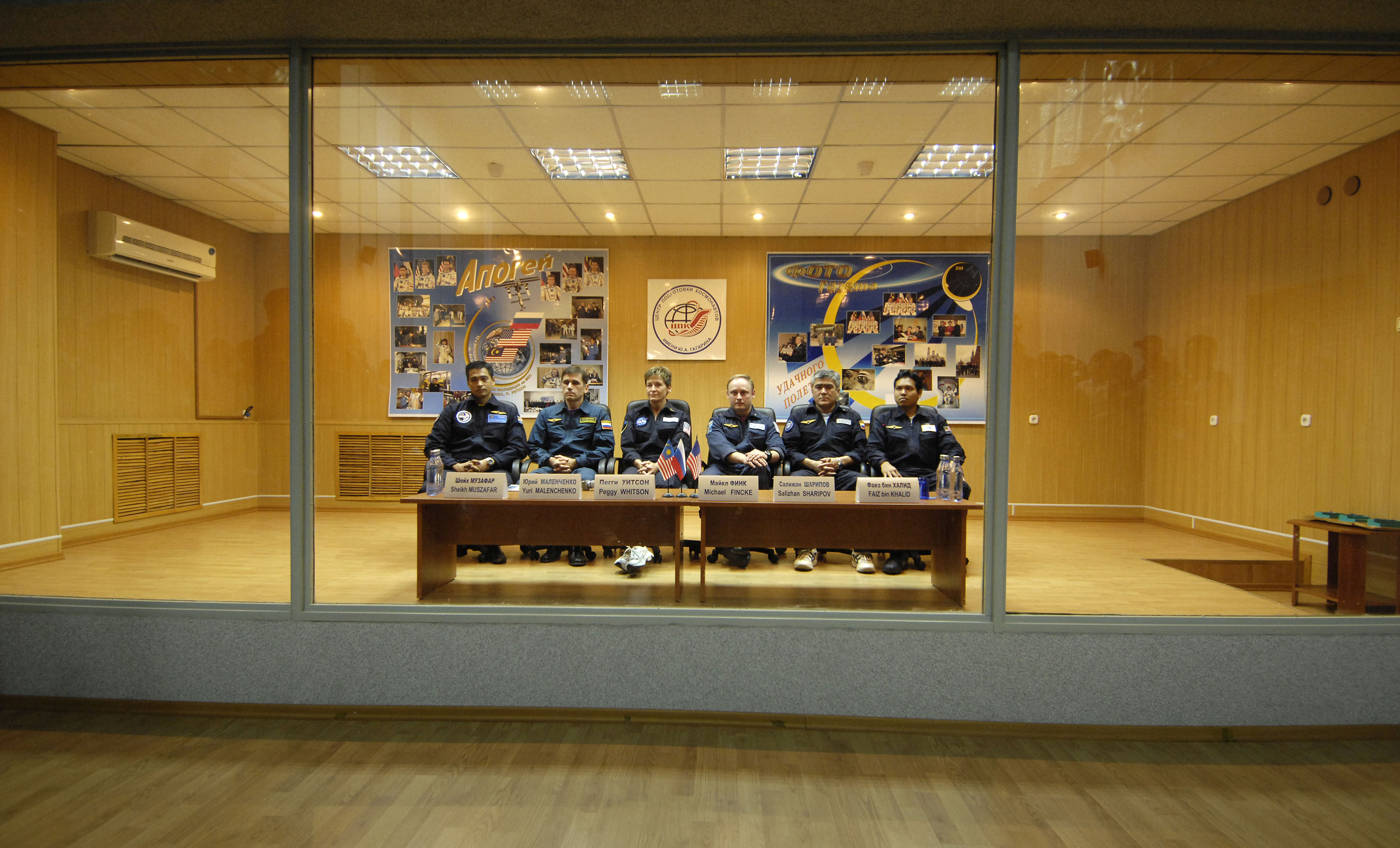 Expedition 16 Commander Peggy Whitson, Flight Engineer and Soyuz Commander Yuri Malenchenko and Malaysian Spaceflight Participant Sheikh Muszhaphar Shukor and their backup crew are protected behind glass during the State Commission meeting and Press Conference Oct. 09, 2007 at the Baikonur Cosmodrome in Kazakhstan. The crew is in preparation for their launch to the International Space Station Oct. 10 in their Soyuz TMA-11 spacecraft. Whitson and Malenchenko will spend six months on the station while Shukor will return to Earth Oct. 21 with two of the Expedition 15 crewmembers currently on the complex. Photo Credit: "NASA/Bill Ingalls"