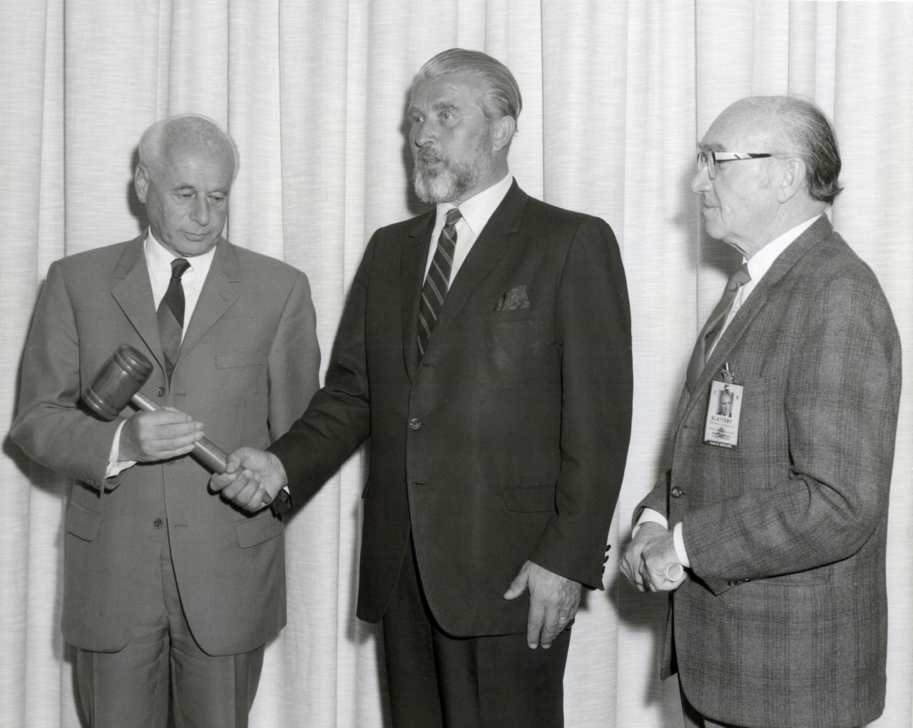 Dr. Wernher Von Braun presents the gavel to incoming center director Dr. Eberhard Rees with Art Slattery looking on.