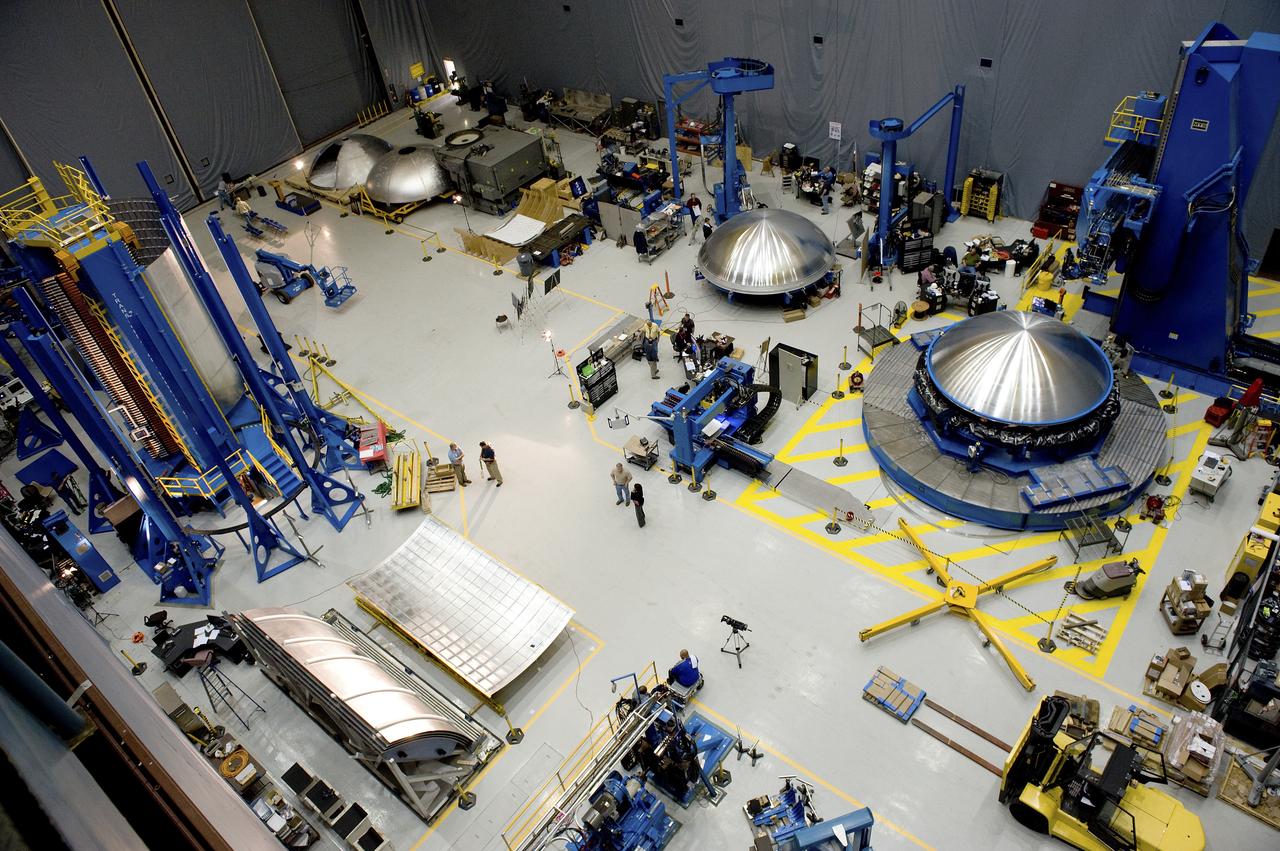 THE OVERHEAD VIEW OF THE FLOOR OF THE FRICTION STIR HIGH BAY AREA IN BUILDING 4755. THIS VIEW SHOWS FOUR DOME PIECES AS WELL AS THE SHELL BUCKLE BARREL PANEL IN THE VERTICAL WELD TOOL