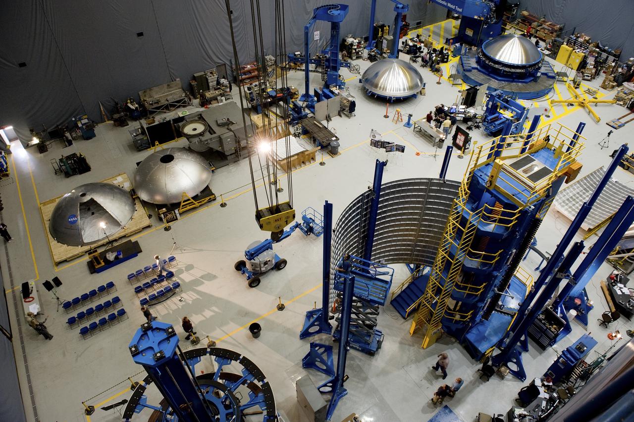 THE OVERHEAD VIEW OF THE FLOOR OF THE FRICTION STIR HIGH BAY AREA IN BUILDING 4755. THIS VIEW SHOWS FOUR DOME PIECES AS WELL AS THE SHELL BUCKLE BARREL PANEL IN THE VERTICAL WELD TOOL