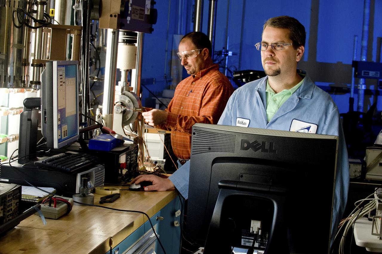NATHAN HORACE STRONG (AEROSPACE ENGINEER, ER31 PROPULSION TURBOMACHINERY DESIGN & DEVELOPMENT BRANCH) AND NATHAN COFFEE (EM10 MATERIALS TEST ENGINEER, JACOBS ESTS GROUP/JTI) ADJUST A UNIQUE MECHANICAL TEST SETUP THAT MEASURES STRAIN ON A SINGLE SAMPLE, USING TWO DIFFERENT TECHNIQUES AT THE SAME TIME. THE TEST FIXTURE HOLDS A SPECIMEN THAT REPRESENTS A LIQUID OXYGEN (LOX) BEARING FROM THE J2-X ENGINE. COFFEY, AT RIGHT, WORK IN A LAB IN BUILDING 4612 ON A BEARING TEST