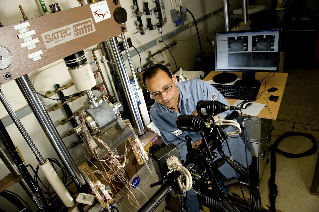 AYMAN GIRGIS (EM10 MATERIALS TEST ENGINEER, JACOBS ESTS GROUP/JTI) ADJUSTS DUAL LENSES FOR A UNIQUE MECHANICAL TST SETUP THAT MEASURES STRAIN ON A SINGLE SAMPLE, USING TWO DIFFERENT TECHNIQUES AT THE SAME TIME. THE TEST FIXTURE HOLDS A SPECIMEN THAT REPRESENTS A LIQUID OXYGEN (LOX) BEARING FROM THE J2-X ENGINE