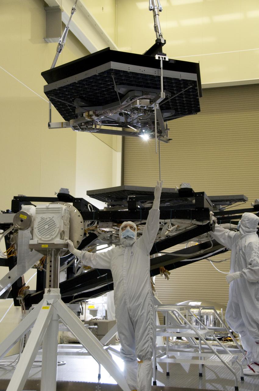 A PRIMARY MIRROR SEGMENT ASSEMBLY BEING CAREFULLY LOWERED TO ITS TEST STAND POSITION ALONGSIDE PREVIOUSLY INSTALLED MIRRORS 