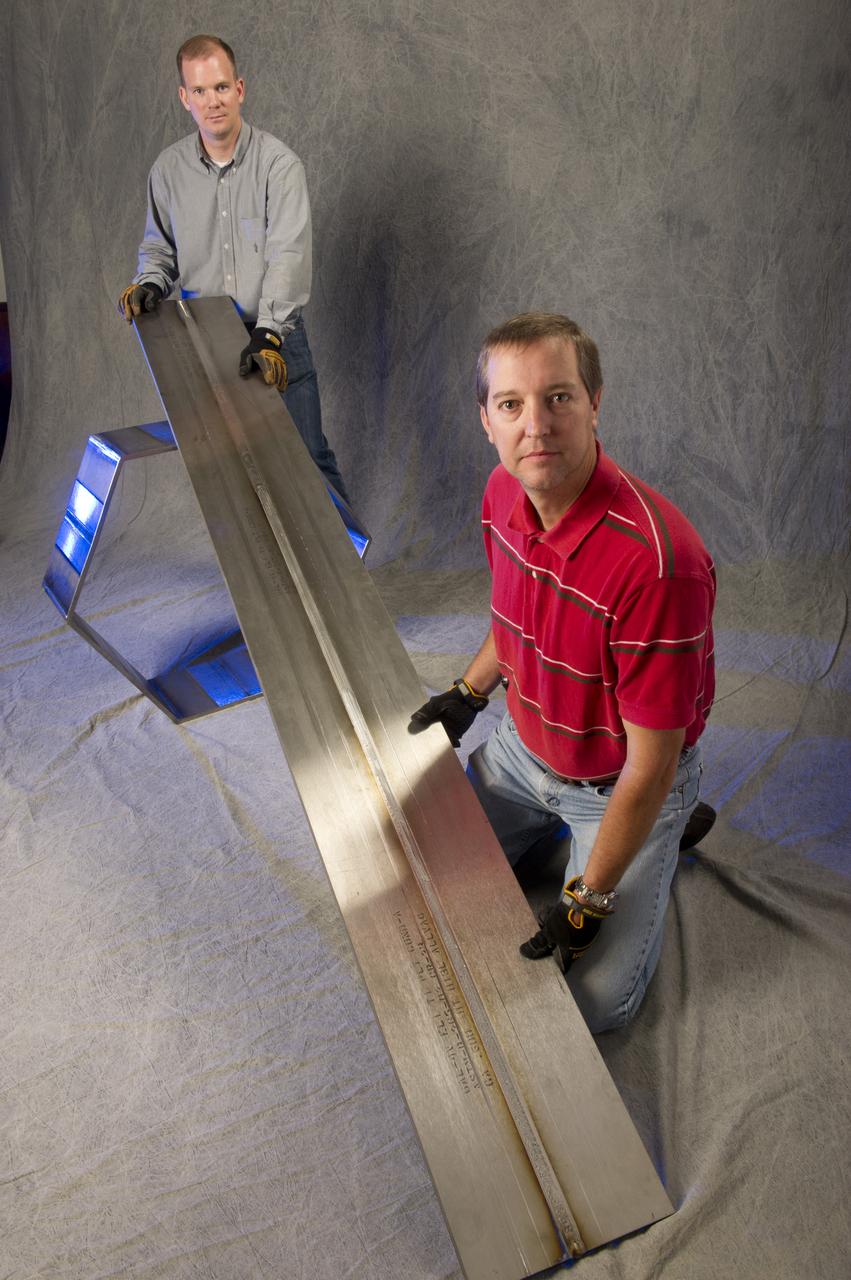 SAMUEL SMITH (WELD TECHNICIAN, JACOBS ESTS GROUP/ALL POINTS) AND ANDRÉ PASEUR (WELD TECHNICIAN, JACOBS ESTS GROUP/ERC) DISPLAY TWO PROCESS DEMONSTRATION ARTICLES – A 9-FOOT BUTT WELD (FOREGROUND) AND A HEXAGON FABRICATED FROM FRICTION STIR WELDED PLATES (BACKGROUND) – THAT WERE FABRICATED FROM 6AL-4V TITANIUM (ELI) USING THERMAL STIR WELDING. THIS WORK WAS PERFORMED FOR A NASA TECHNOLOGY TRANSFER INDUSTRIAL PARTNER (KEYSTONE SYNERGETIC ENTERPRISES, INC.) IN SUPPORT OF A PROJECT FOR THE U.S. NAVY