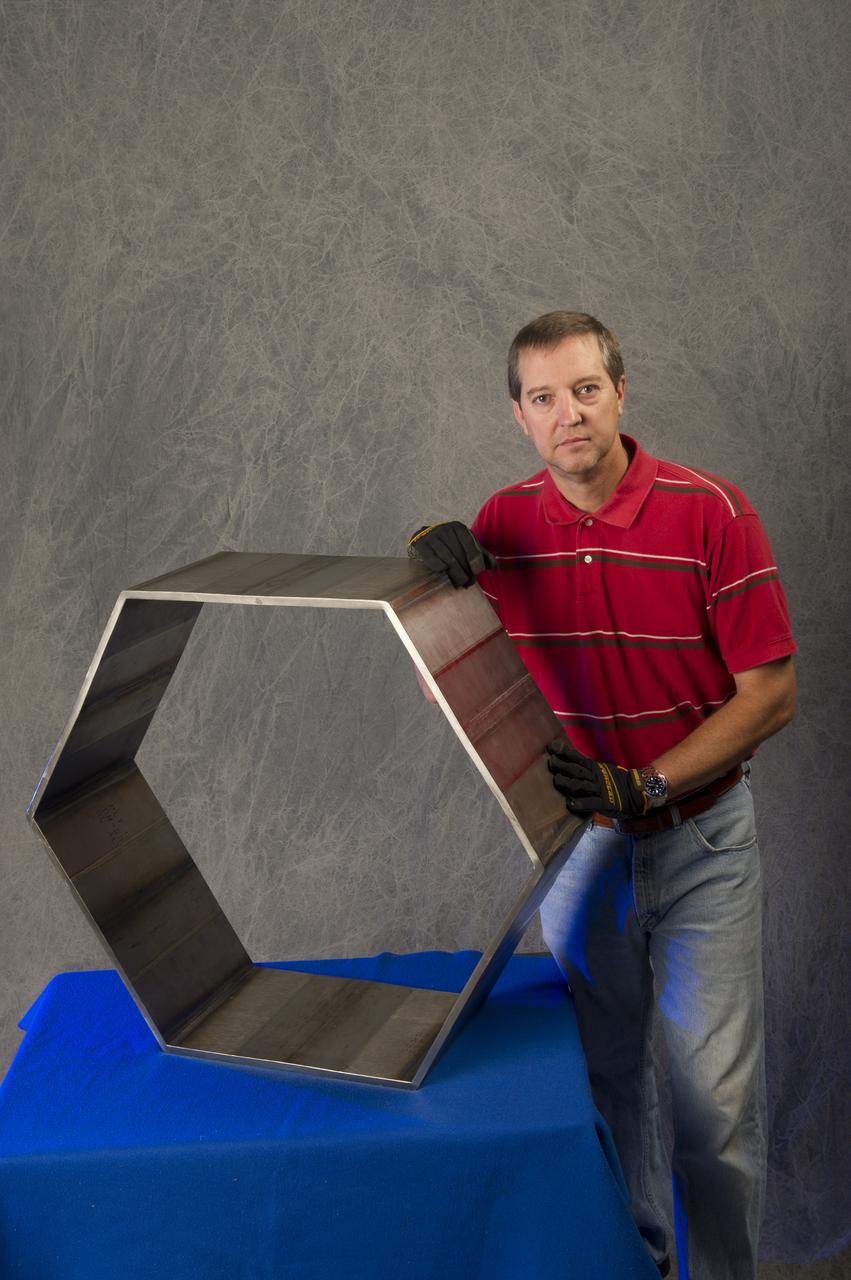 ANDRÉ PASEUR (WELD TECHNICIAN, JACOBS ESTS GROUP/ERC) DISPLAYS A HEXAGON THAT WAS FABRICATED FROM FRICTION STIR WELDED PLATES OF 6AL-4V TITANIUM (ELI) USING THERMAL STIR WELDING. THIS WORK WAS PERFORMED FOR A NASA TECHNOLOGY TRANSFER INDUSTRIAL PARTNER (KEYSTONE SYNERGETIC ENTERPRISES, INC.) IN SUPPORT OF A PROJECT FOR THE U.S. NAVY