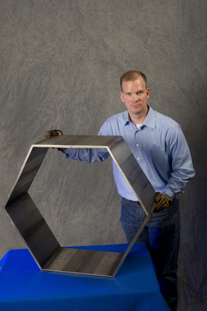 SAMUEL SMITH (WELD TECHNICIAN, JACOBS ESTS GROUP/ALL POINTS) DISPLAYS A HEXAGON THAT WAS FABRICATED FROM FRICTION STIR WELDED PLATES OF 6AL-4V TITANIUM (ELI) USING THERMAL STIR WELDING. THIS WORK WAS PERFORMED FOR A NASA TECHNOLOGY TRANSFER INDUSTRIAL PARTNER (KEYSTONE SYNERGETIC ENTERPRISES, INC.) IN SUPPORT OF A PROJECT FOR THE U.S. NAVY