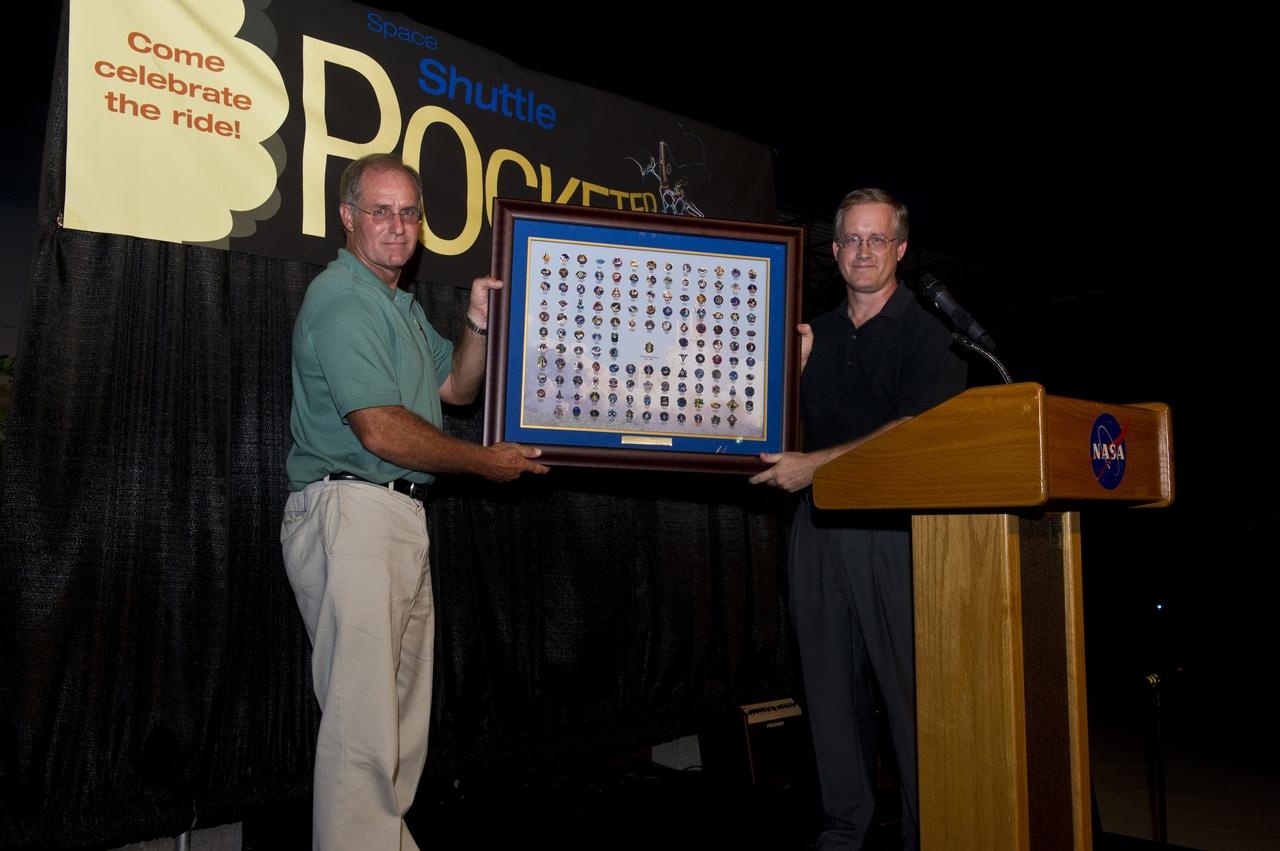 MARSHALL SHUTTLE PROPULSION OFFICE MANAGER STEVE CASH PRESENTS A MISSION PIN PLAQUE TO JOHN SHANNON, MANAGER OF THE SPACE SHUTTLE PROGRAM.