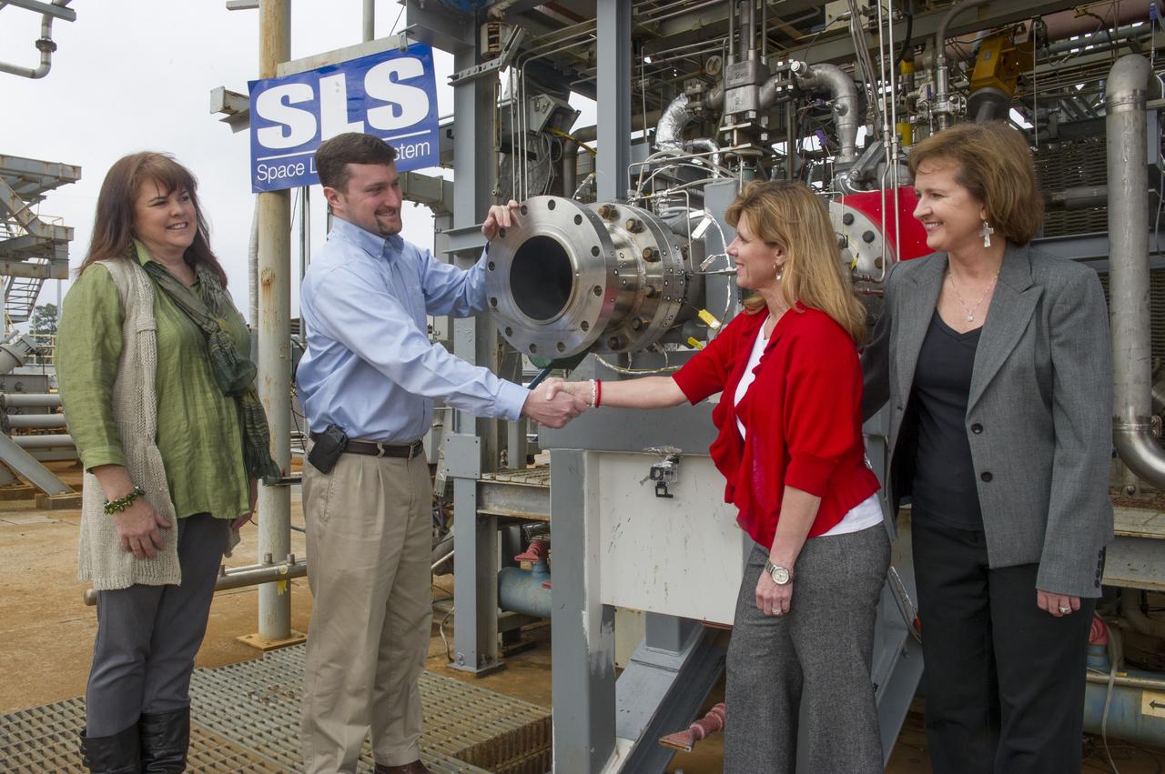 FROM LEFT TO RIGHT IN FRONT OF THE F-1 GAS GENERATOR ARE: DYNETICS PROGRAM MANAGER KIM DOERING, DYNETICS DEPUTY PROGRAM MANAGER ANDY CROCKER, MARSHALL PARTNERSHIPS MANAGER STACY COUNTS,  AND MARSHALL PROJECT MANAGER FOR DYNETICS WHITNEY YOUNG. 
