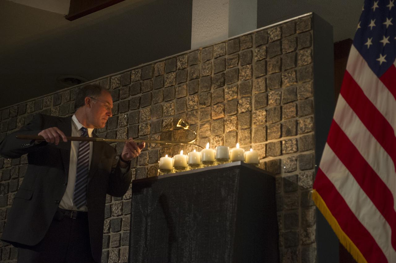 STEVE CASH LIGHTS CANDLES IN REMEMBRANCE OF THOSE WHO HAVE LOST THEIR LIVES IN PURSUIT OF SPACE EXPLORATION.