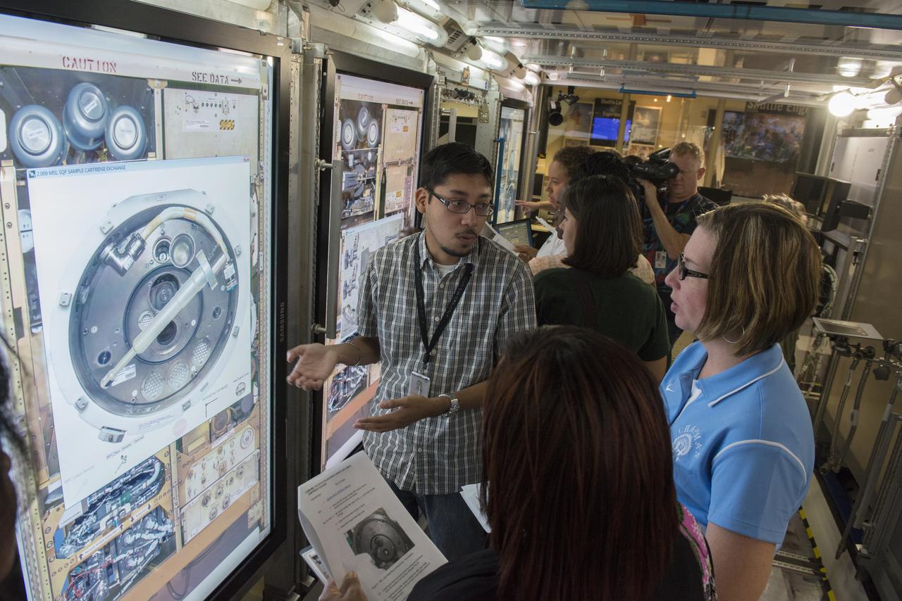 VINCENT VIDAURRI, CENTER, A TECHNICAL SPECIALIST WITH TELEDYNE BROWN ENGINEERING SUPPORTING MISSION OPERATIONS AT THE MARSHALL SPACE FLIGHT CENTER, PROVIDES DETAILS ABOUT A MOCK-UP OF THE INTERNATIONAL SPACE STATION SCIENCE LAB TO A GROUP OF AREA TEACHERS AS PART OF "BACK-2-SCHOOL DAY." TEAM REDSTONE -- WHICH INCLUDES THE MARSHALL SPACE FLIGHT CENTER AND U.S. ARMY ORGANIZATIONS ON REDSTONE ARSENAL -- INVITED 50 TEACHERS TO TOUR REDSTONE ARSENAL AUG. 15, GIVING THEM AN OPPORTUNITY TO LEARN OF AND SEE RESOURCES AVAILABLE TO THEM AND THEIR STUDENTS. THE TOUR FOCUSED ON SITES AVAILABLE FOR FIELD TRIPS FOR STUDENTS STUDYING MATH, SCIENCE, TECHNOLOGY AND ENGINEERING. STOPS INCLUDED MARSHALL'S PAYLOAD OPERATIONS INTEGRATION CENTER AND THE HIGH SCHOOLS UNITED WITH NASA TO CREATE HARDWARE LAB, OR HUNCH, BOTH LOCATED IN BUILDING 4663. THE PROGRAM GIVES HIGH SCHOOL STUDENTS THE CHANCE TO WORK WITH NASA ENGINEERS TO DESIGN AND BUILD HARDWARE FOR USE ON THE INTERNATIONAL SPACE STATION. THE TEACHERS ALSO VISITED THE ARMY AVIATION & MISSILE RESEARCH DEVELOPMENT & ENGINEERING CENTER AND THE REDSTONE TEST CENTER