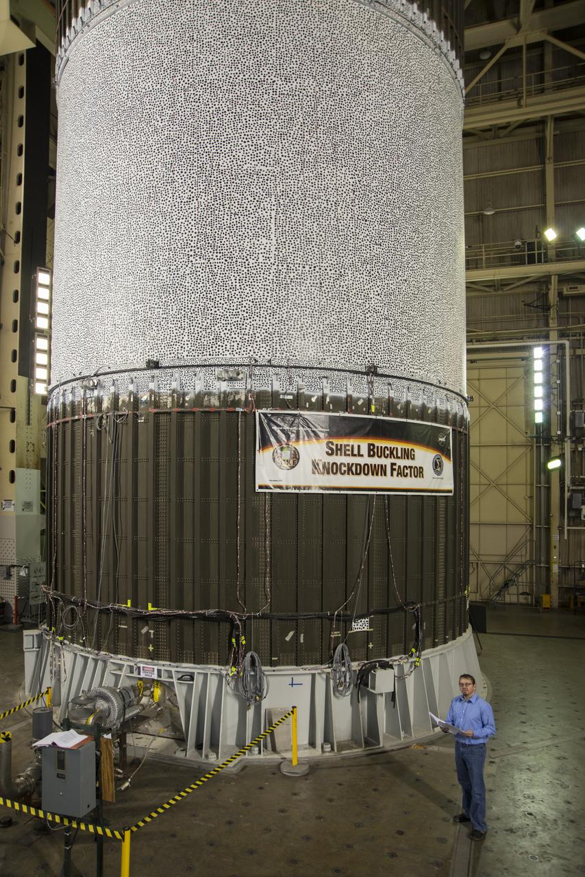 MARK HILBURGER, PROJECT ENGINEER FROM LANGLEY RESEARCH CENTER (LARC) WITH THE ALUMINUM-LITHIUM CYLINDER USED IN THE SHELL BUCKLE KNOCKDOWN FACTOR TESTING. DURING THE TESTING FORCE AND PRESSURE WERE INCREASINGLY APPLIED TO THE TOP OF AN EMPTY BUT PRESSURIZED ROCKET FUEL TANK TO EVALUATE ITS STRUCTURAL INTEGRITY.