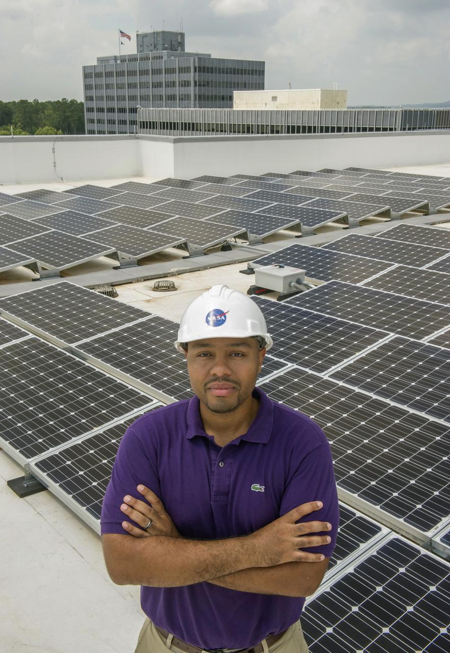 BYRON L. WILLIAMS, FACILITIES MECHANICAL ENGINEER, STANDING ON THE ROOF OF BUILDING 4220 IN FRONT OF THE SOLAR ENERGY PANELS.