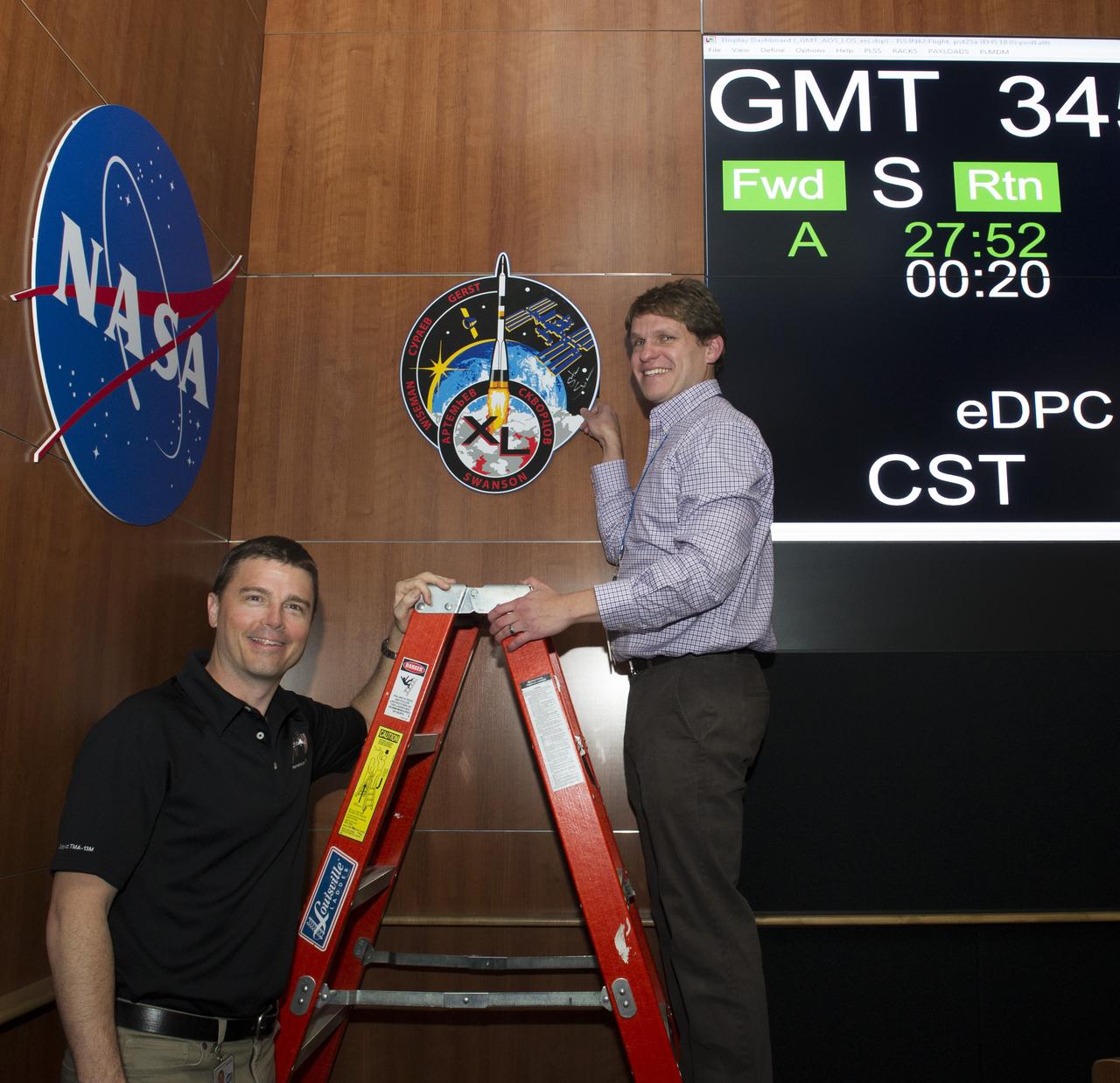 RYAN MILLER, RIGHT, LEAD PAYLOAD PLANNING MANAGER FOR EXPEDITION 39/40 WITH THE PAYLOAD OPERATIONS INTEGRATION CENTER AT THE MARSHALL SPACE FLIGHT CENTER, HELPS NASA ASTRONAUT REID WISEMAN PREPARE TO AUTOGRAPH THE INTERNATIONAL SPACE STATION EXPEDITION 40 MISSION PLAQUE HANGING IN THE POIC. WISEMAN VISITED THE MARSHALL CENTER DEC. 11 FOR A MEETING WITH THE MARSHALL-BASED PAYLOAD OPERATIONS TEAM HE WORKED WITH DURING HIS SIX MONTHS ON THE ORBITING LABORATORY, DISCUSSING THE FINER POINTS OF THE INVESTIGATIONS PERFORMED ON THE SPACE STATION FROM JUNE THROUGH NOVEMBER 2014.