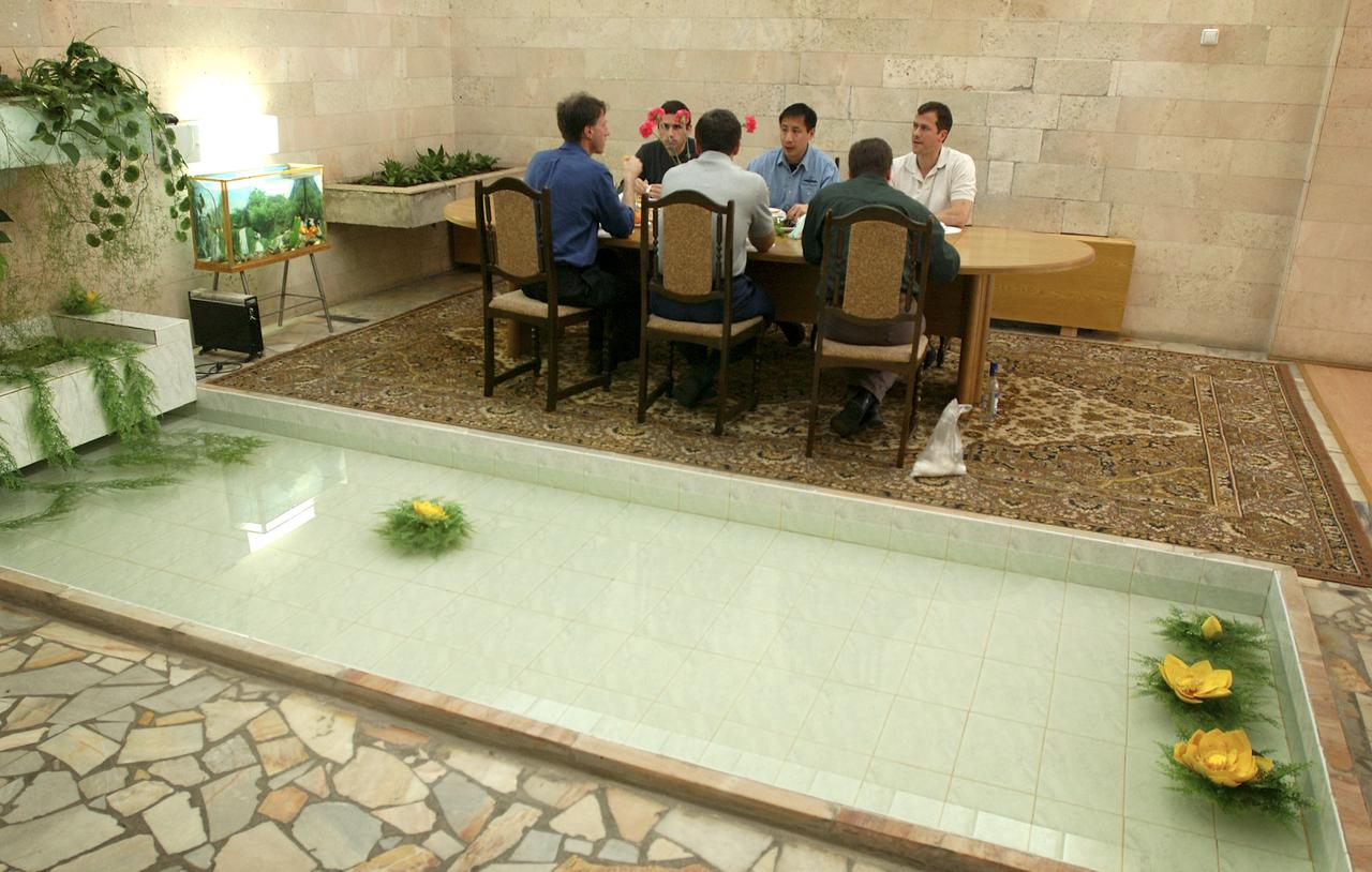 Expedition 7 Commander, Yuri I. Malenchenko, second from left, facing camera, NASA International Space Station Science Officer and Flight Engineer, Edward T. Lu, center, and prime crew Flight Surgeon Thomas Marshburn eat dinner at the Cosmonaut Hotel along with the backup crew members, astronaut Michael Foale, left, back to camera, cosmonaut Alexander Kaleri, center, back to camera, and an unidentified Russian flight surgeon in Baikonur, Kazakhstan, Wednesday, April 9, 2003. Photo Credit: (NASA/Bill Ingalls)