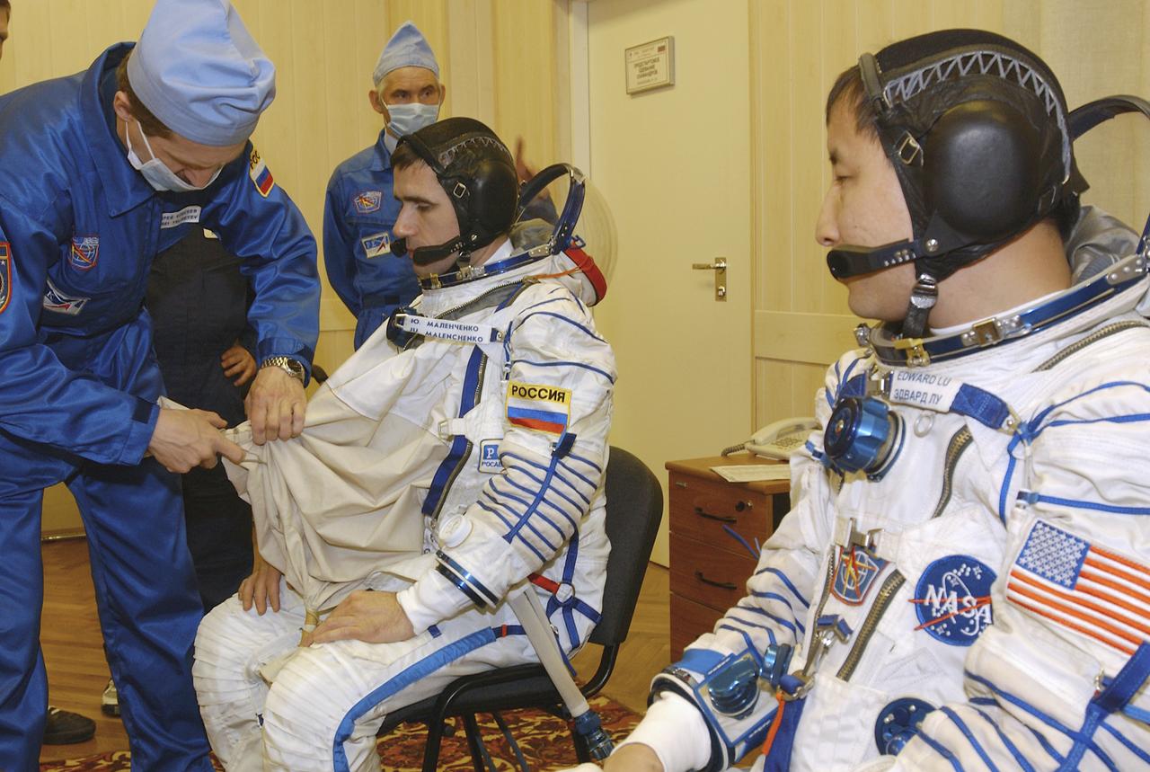 Expedition 7 Commander Yuri I. Malenchenko, center, dons his Russian Sokol suit for the leak check, seat liner check and Soyuz inspection at the Soyuz Integration Facility at the Baikonur Cosmodrome in Baikonur, Kazakhstan, Thursday, April 10, 2003. Seated next to him is astronaut Edward T. Lu, NASA International Space Station Science Officer and Flight Engineer for Expedition 7. Photo Credit: (NASA/Bill Ingalls)