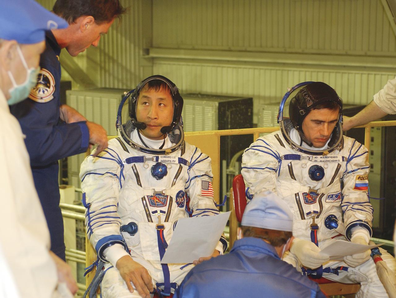 Expedition 7 backup crew member Michael Foale, left, talks with Expedition 7 NASA International Space Station Science Officer and Flight Engineer Edward T. Lu and Expedition 7 Commander Yuri I. Malenchenko, right, as they review documents prior to entering the Soyuz TMA-2 capsule for inspection and seat liner check in the Soyuz Integration Facility at the Baikonur Cosmodrome, in Baikonur, Kazakhstan, Thursday, April 10, 2003. Photo Credit: (NASA/Bill Ingalls)