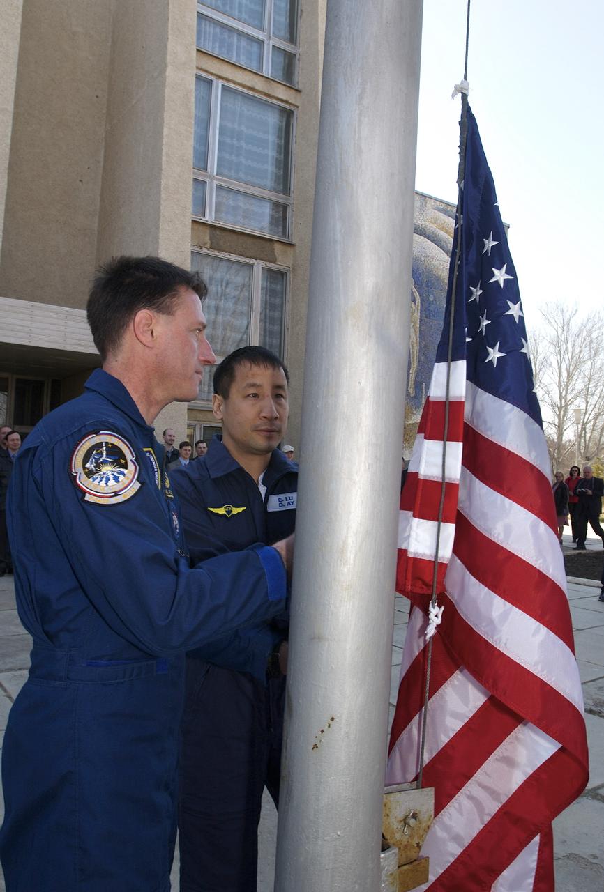 Expedition 7 backup crew member Michael Foale, left and Edward T. Lu, NASA International Space Station Science Officer and Flight Engineer, participate in the ceremonial flag raising at the Cosmonaut Hotel, Kazakhstan, Monday, April 21, 2003. Photo Credit: (NASA/Scott Andrews)