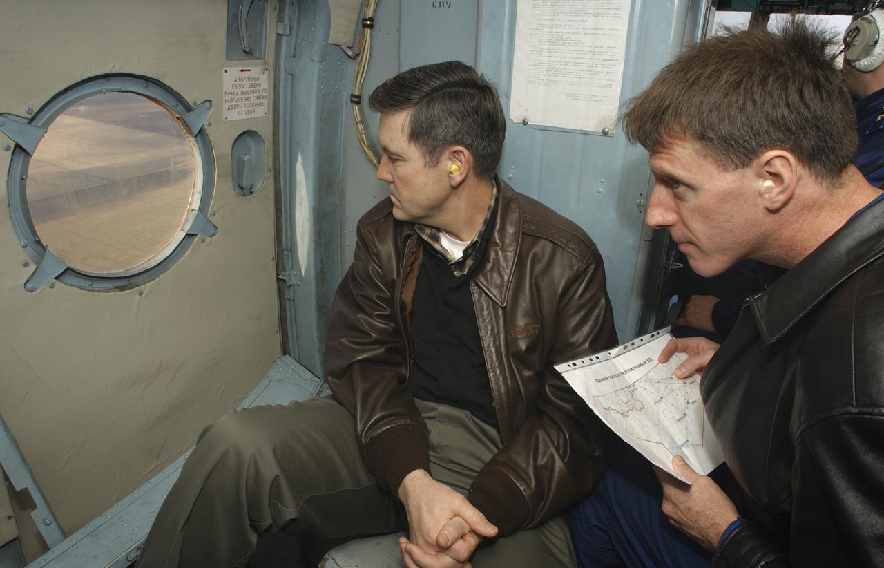 From the seat of a Russian helicopter, Bob Cabana, left, Director of Flight Crew Operations and astronaut Michael Foale look out over the Kazakh terrain for the Expedition 6 Soyuz capsule after its landing on Tuesday, May 4, 2003, in Kazakhstan.  Photo Credit: (NASA/Bill Ingalls)