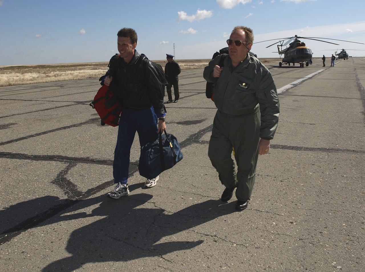 Astronaut Michael Foale, left, and Mike Duncan, Expedition 6 Lead Flight Surgeon, move to another helicopter after the landing team helicopters returned for refueling, Tuesday, May 4, 2003, in Kazakhstan.  Foale and Duncan went on from the refueling to meet the crew of Expedition 6 at the landing site.  Photo Credit: (NASA/Bill Ingalls)